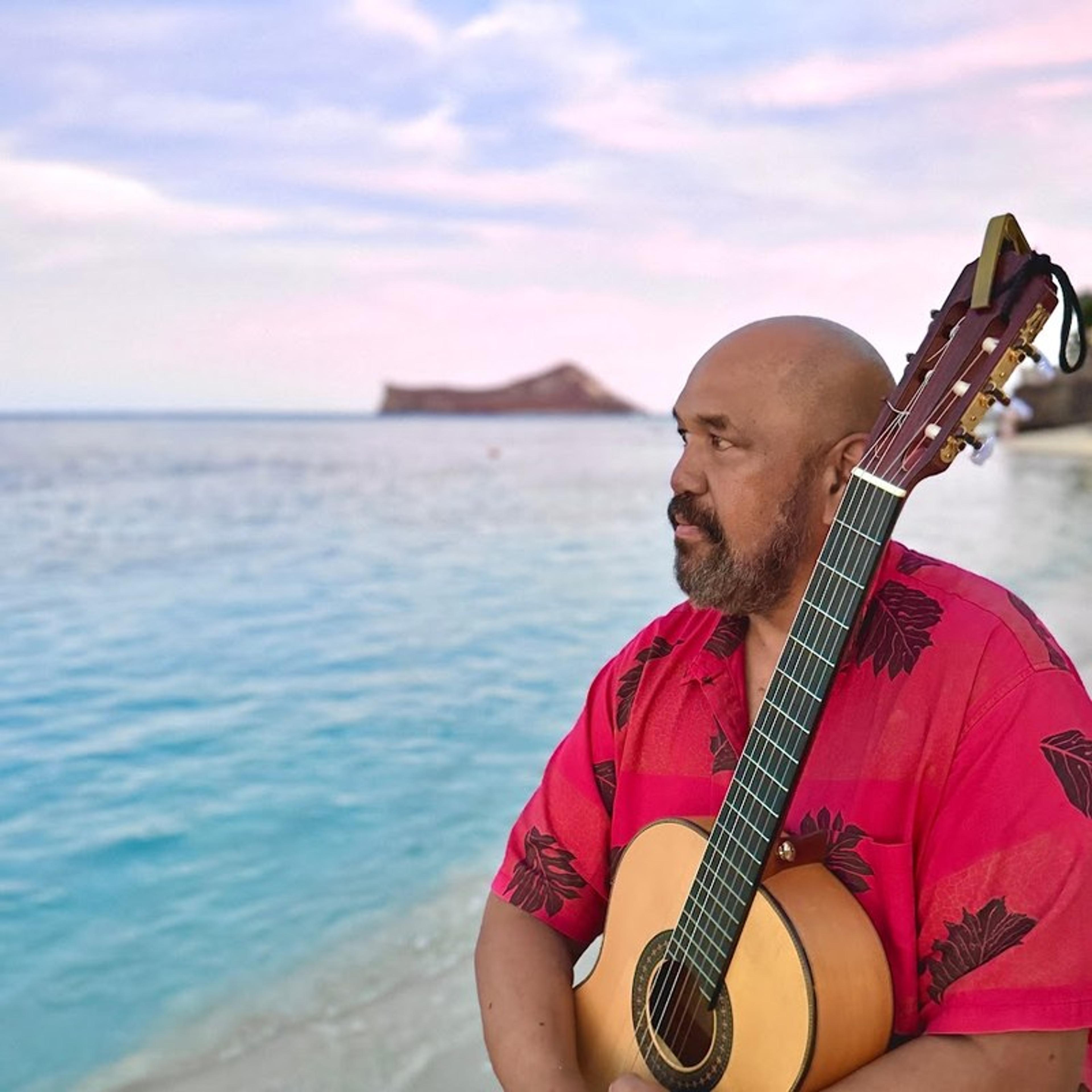 Kawika Kahiapo with his guitar at the shore
