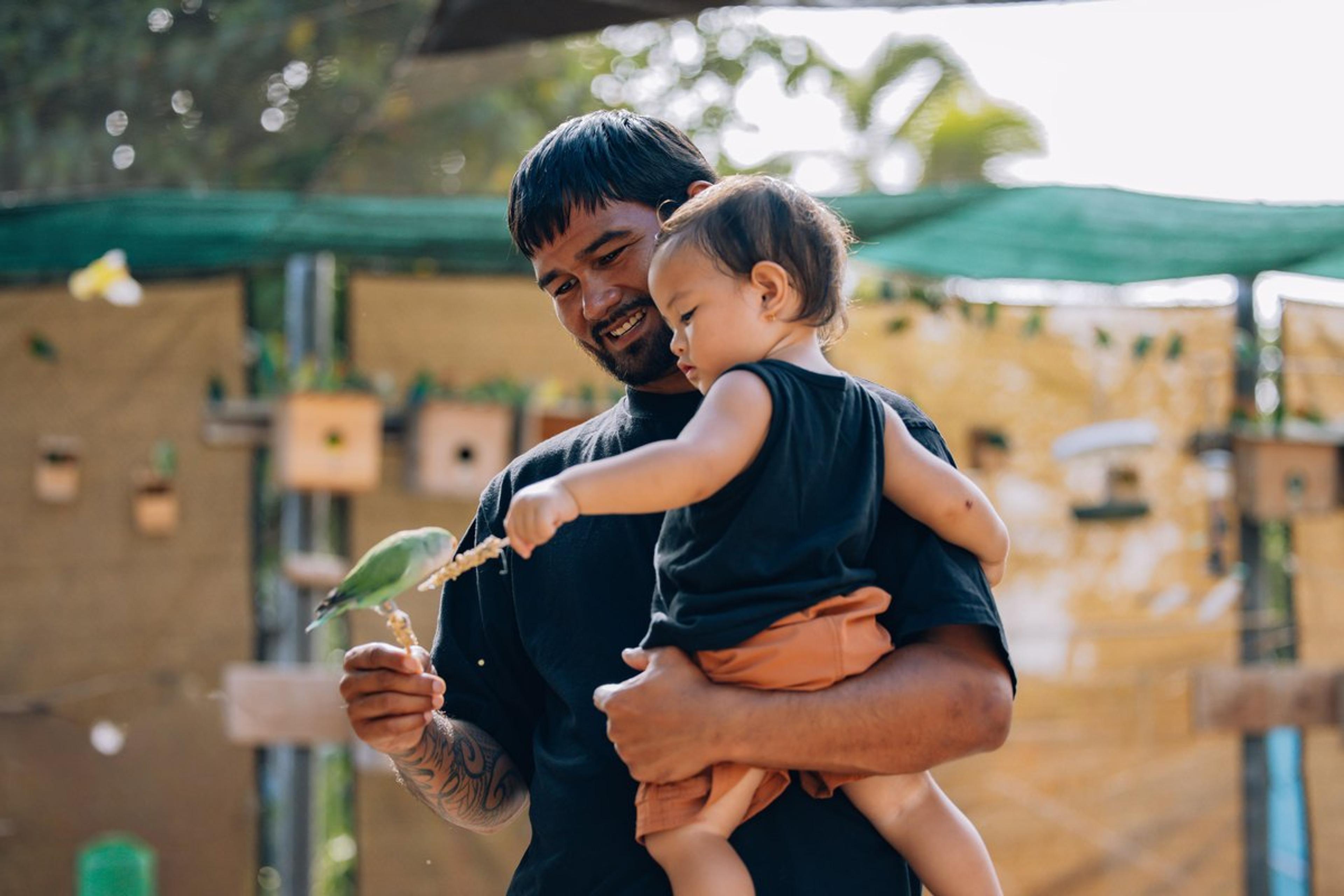 A father and keiki feeding a lorikeet