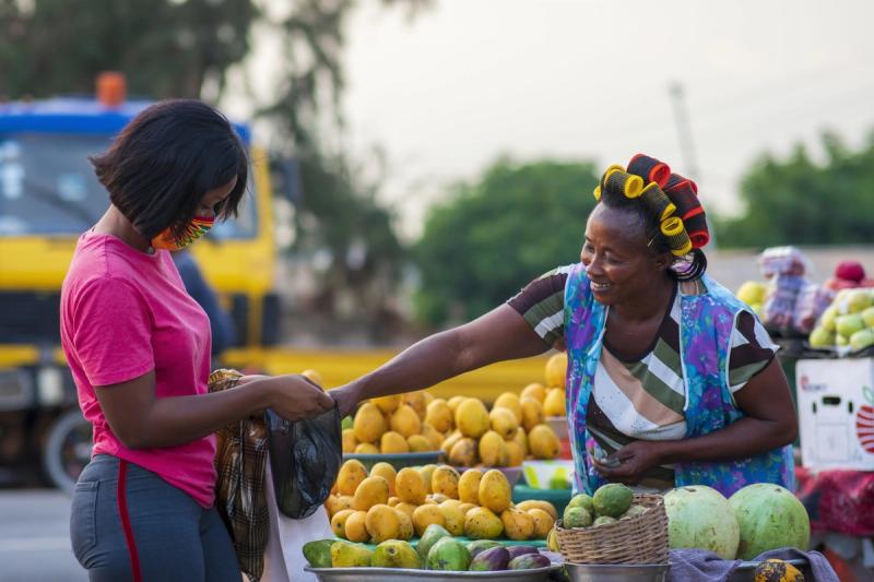A shopper paying a trader for fruit at an open-air market