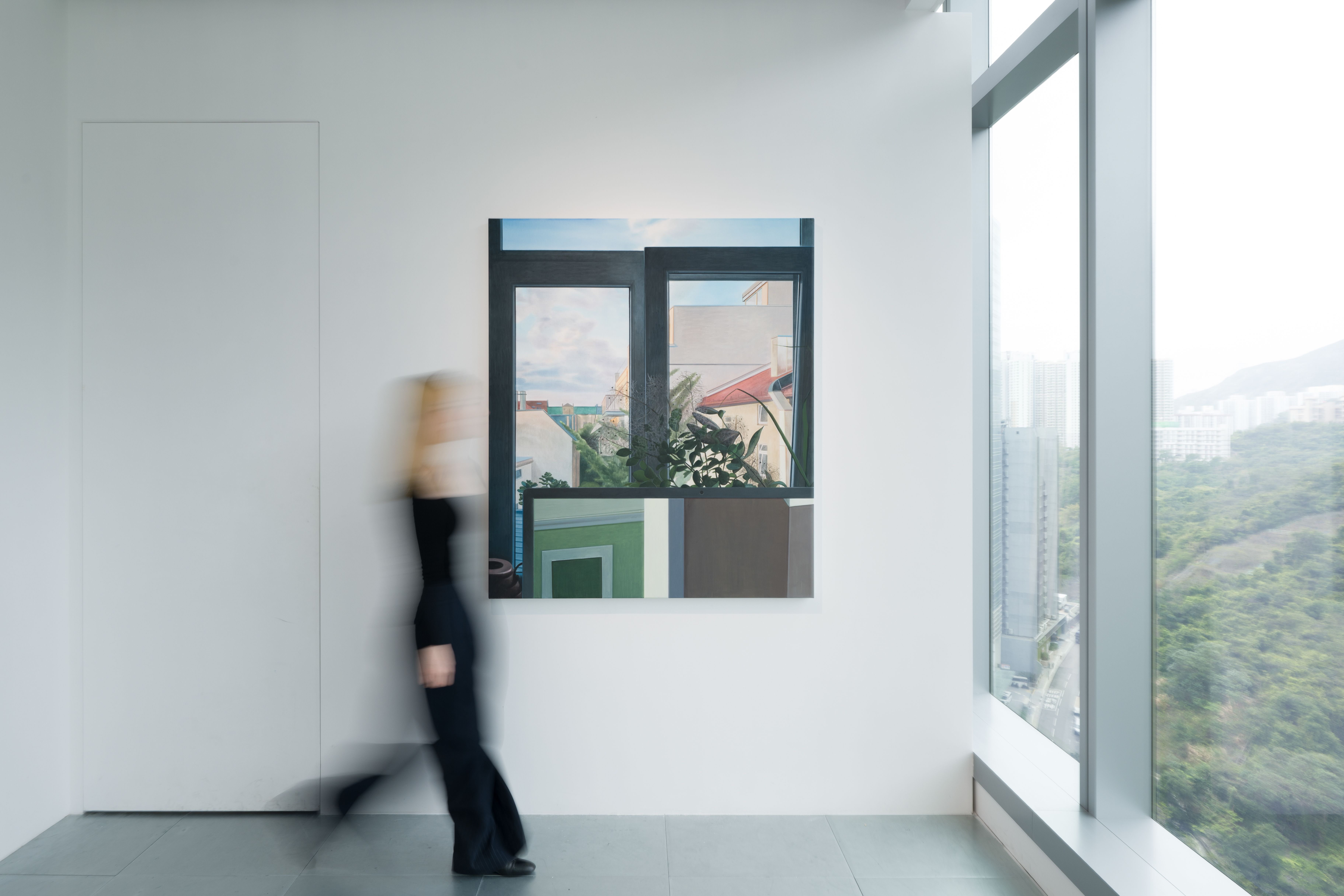 An installation shot of a painting showing a window and a screen with a person walking through the frame