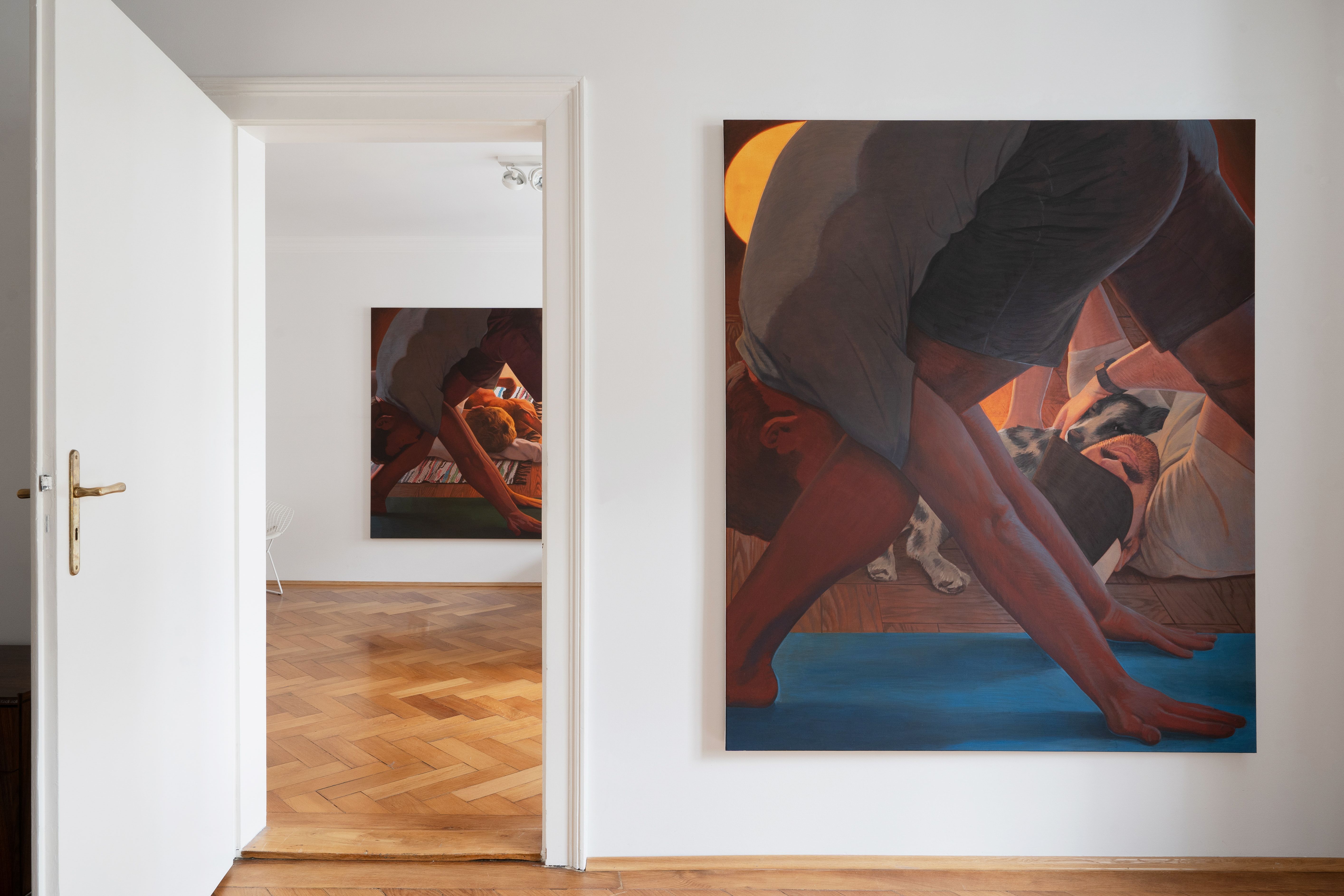 Installation shot of a painting in a domestic setting, the painting shows a man doing yoga and another man rolling on the floor with a dog