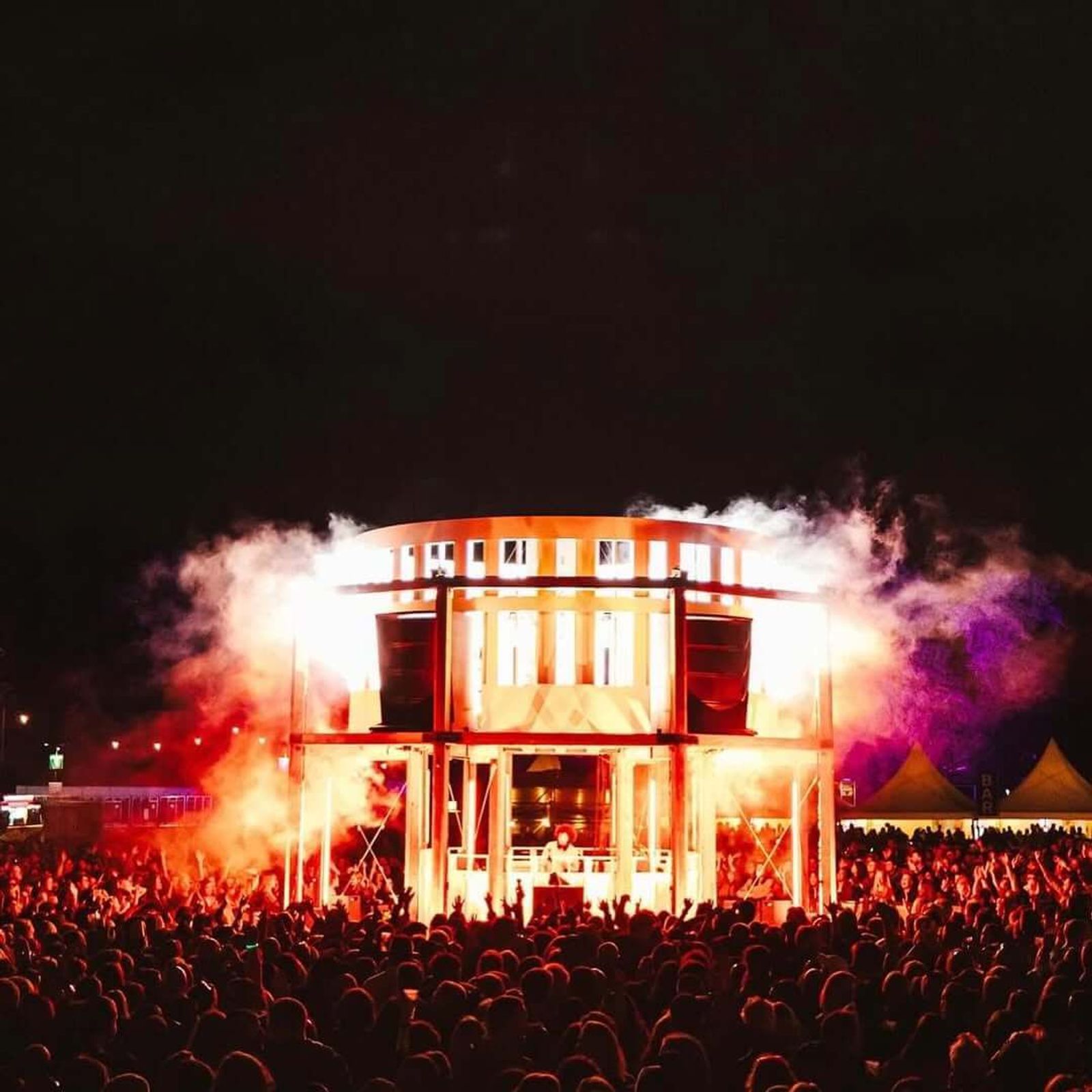 A festival stage lit up with pyrotechnics at night
