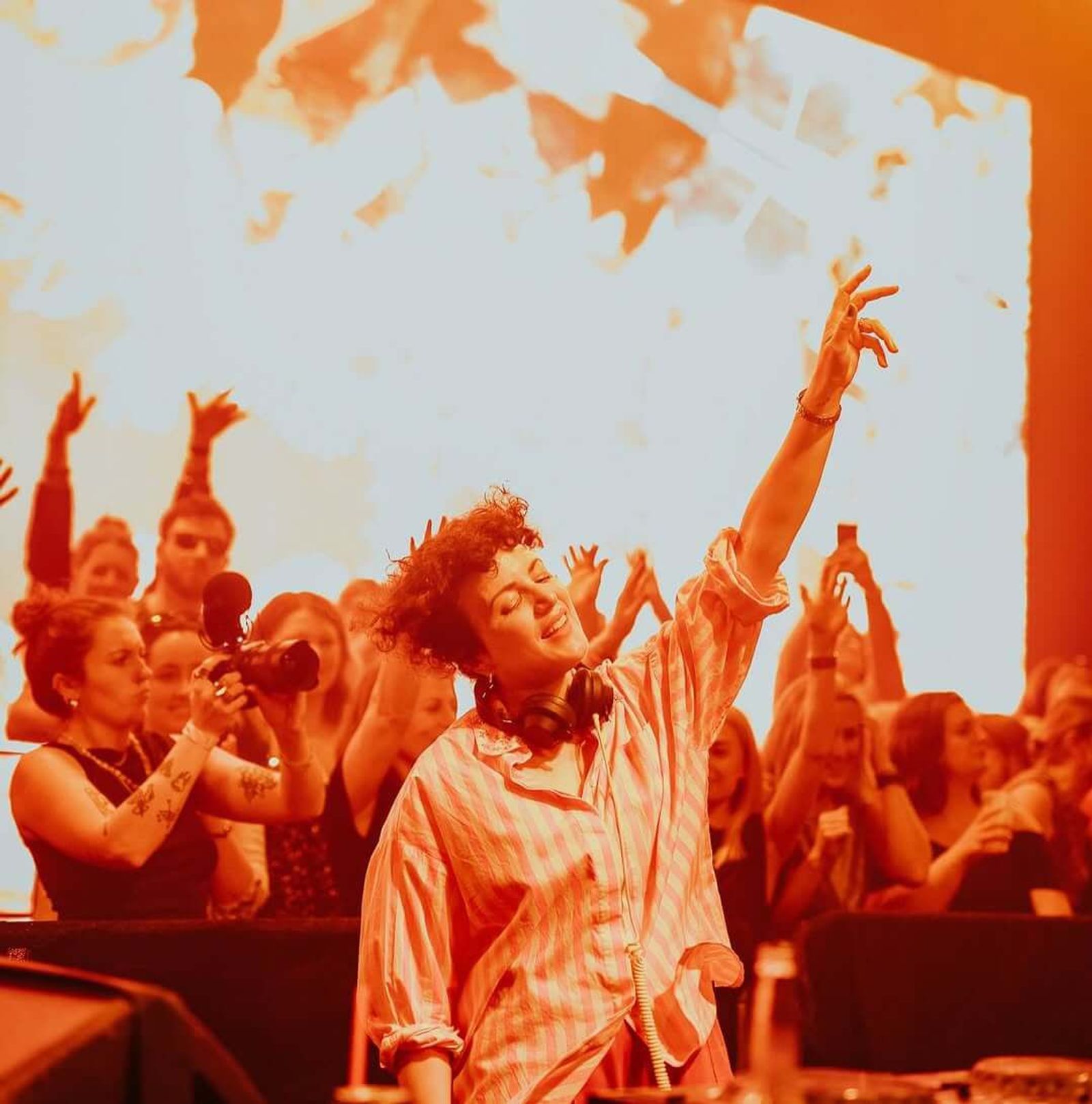 Annie with her arms raised in front of a sunlit crowd
