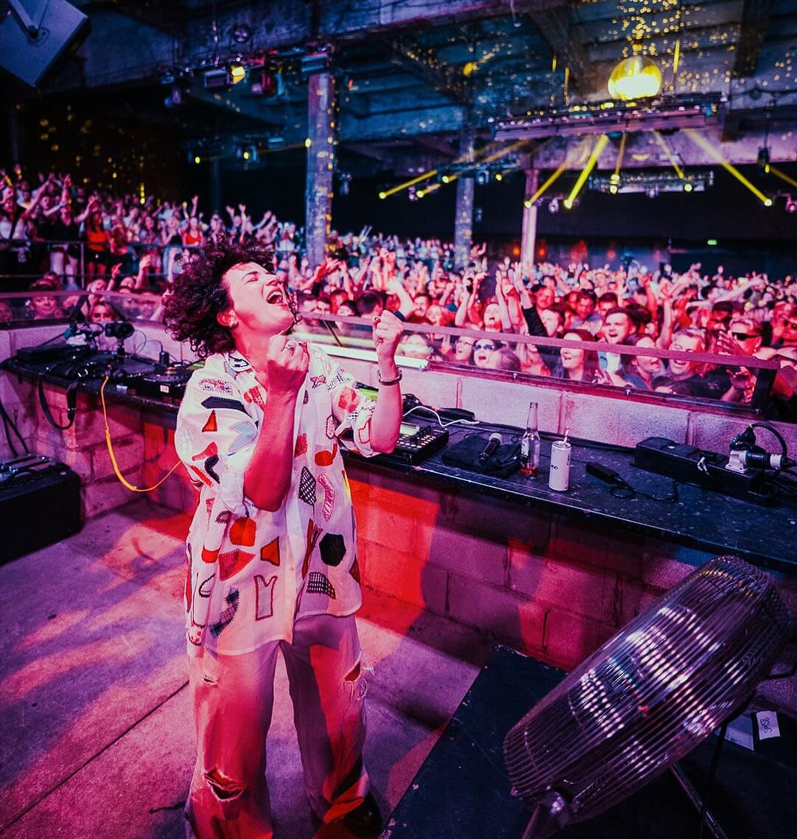 Annie Macmanus DJing, arms raised above the decks