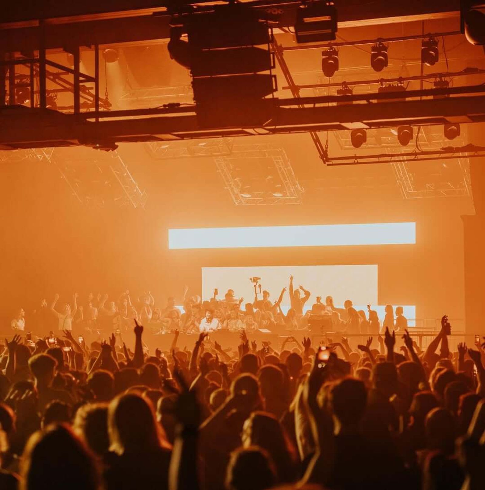 An amber-lit warehouse crowd