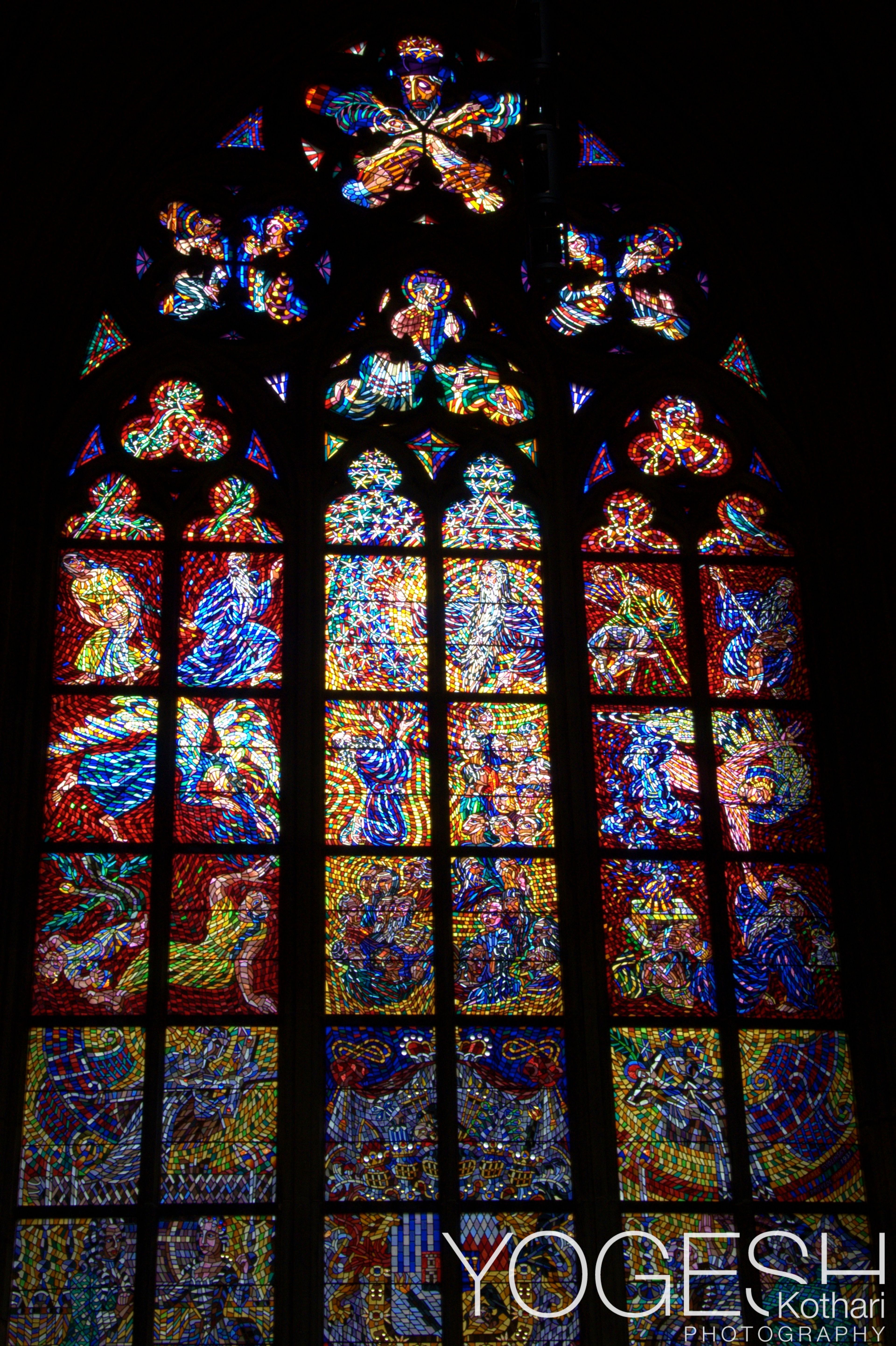 Tall Gothic stained-glass window glowing red, blue and gold