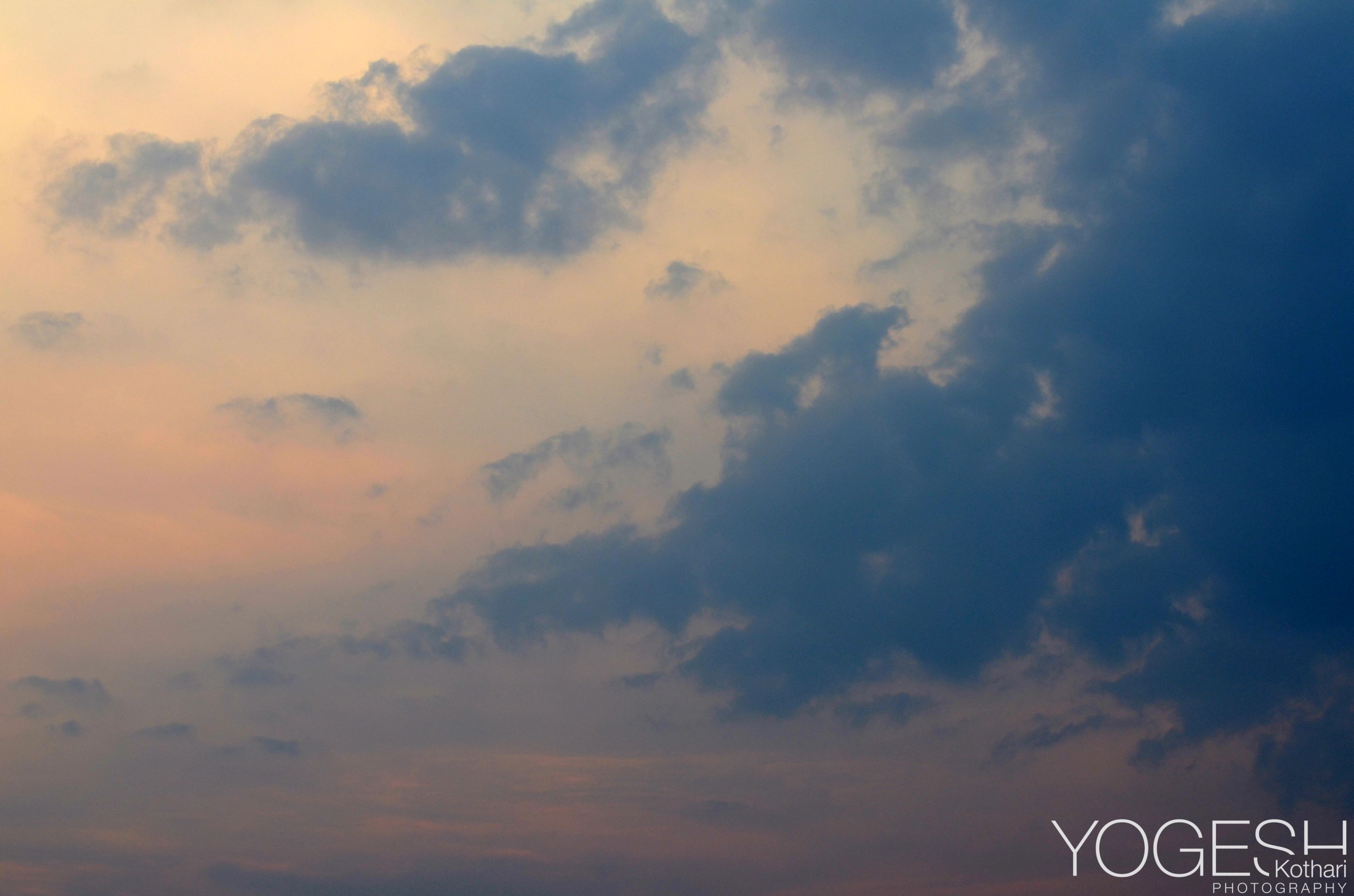 Soft pink and orange light spreading behind dark blue clouds