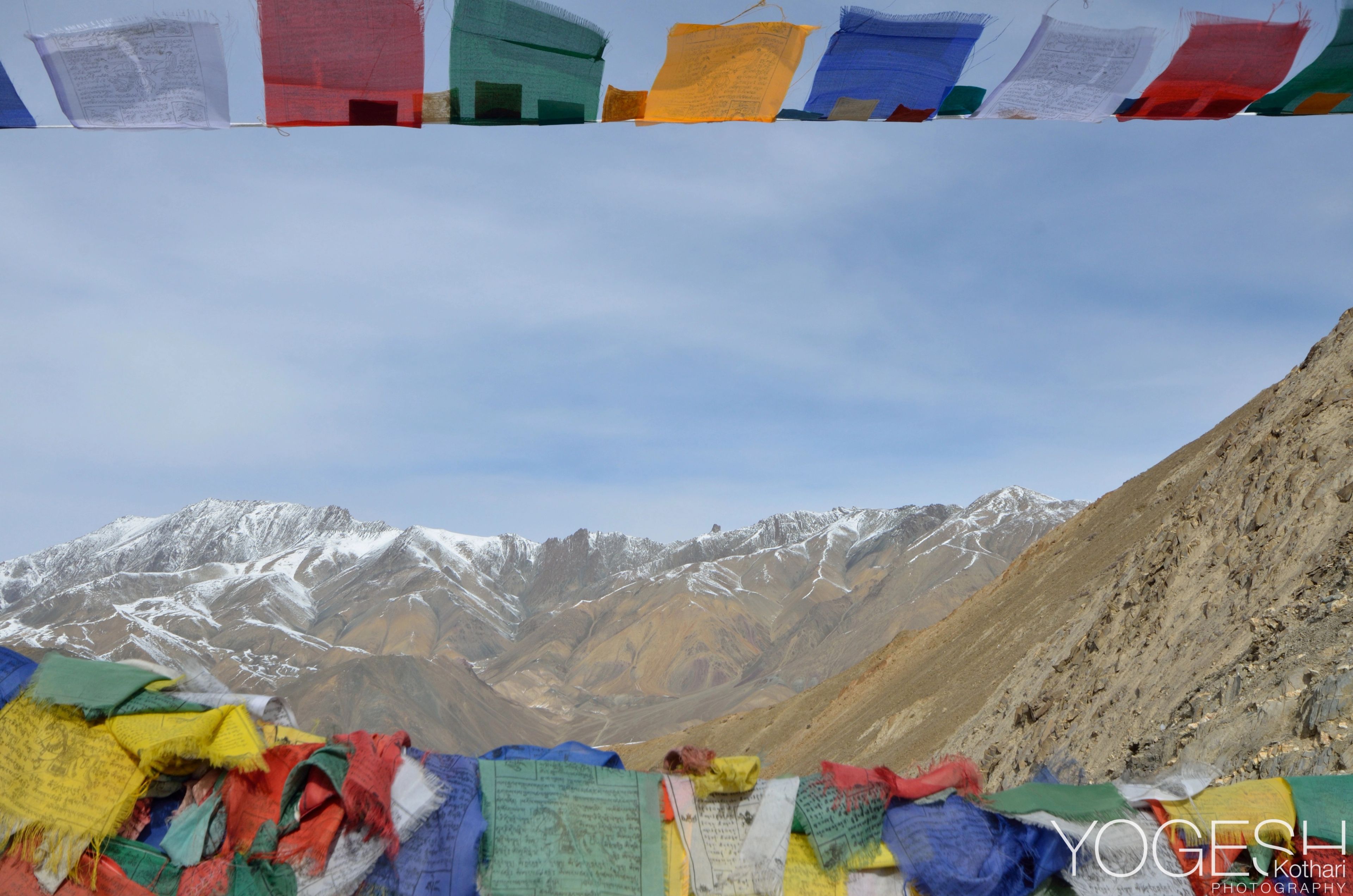 Rows of colourful prayer flags framing snow-capped mountains and a blue sky