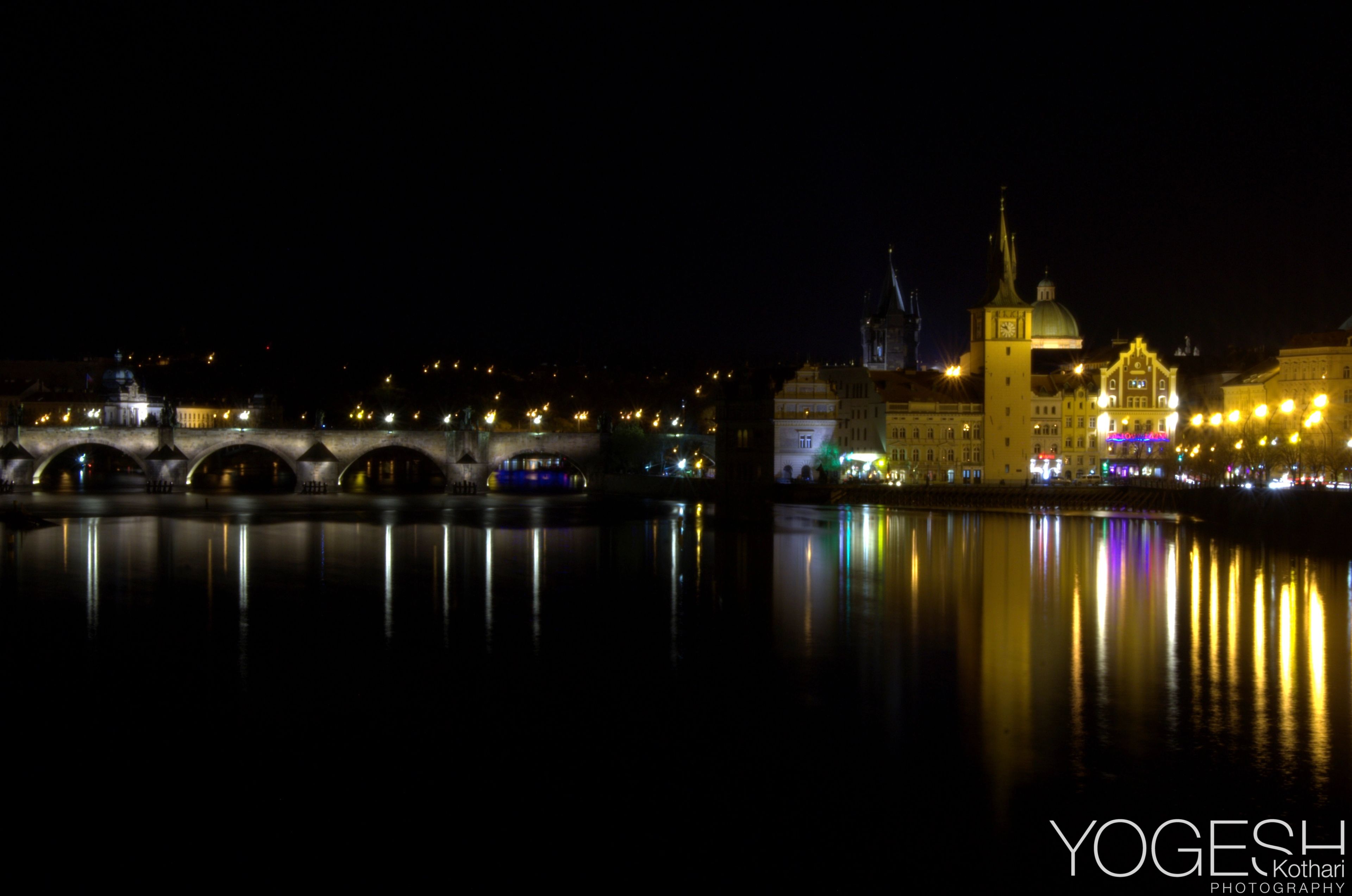 Old stone bridge and city lights reflected in a river at night