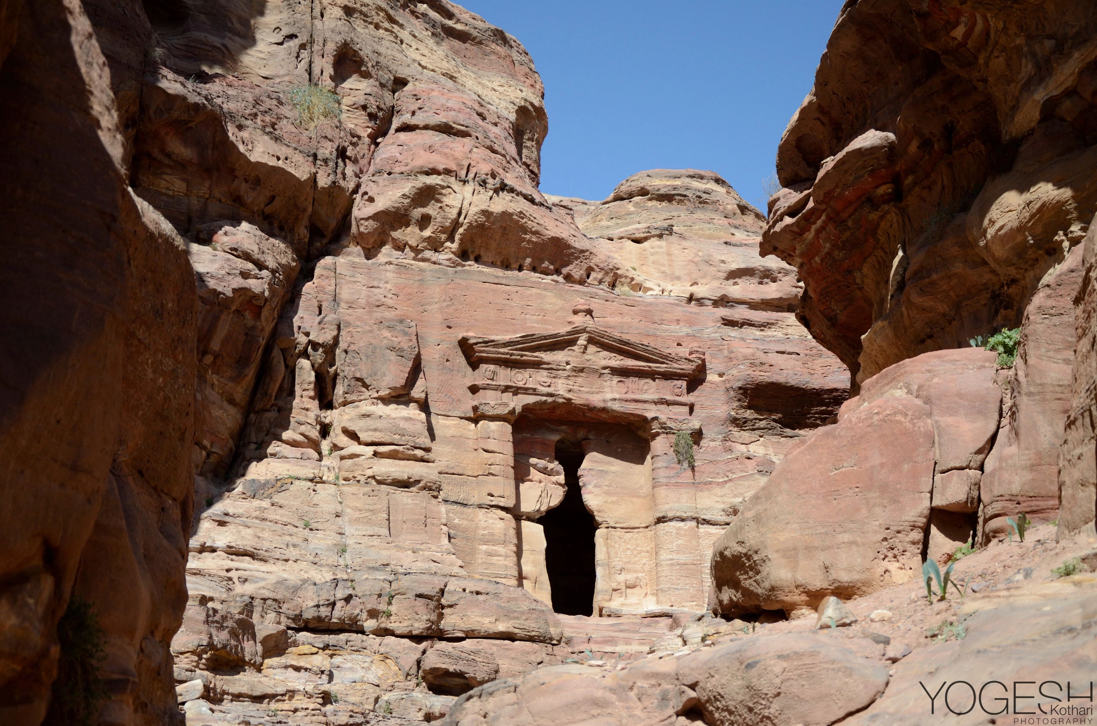 Doorway and carved facade cut into pink sandstone rock in Petra