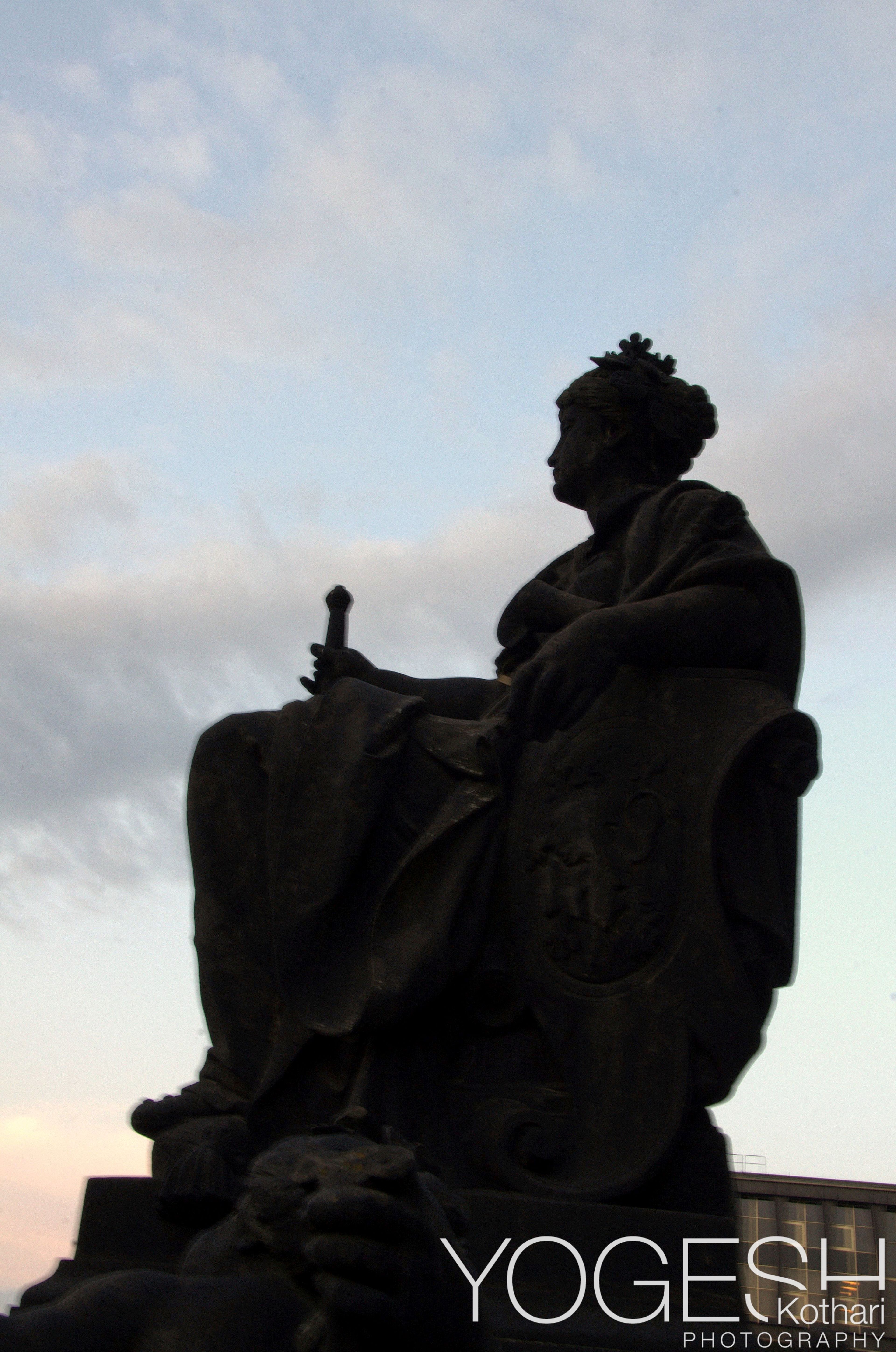 Seated statue silhouetted against a dusk sky