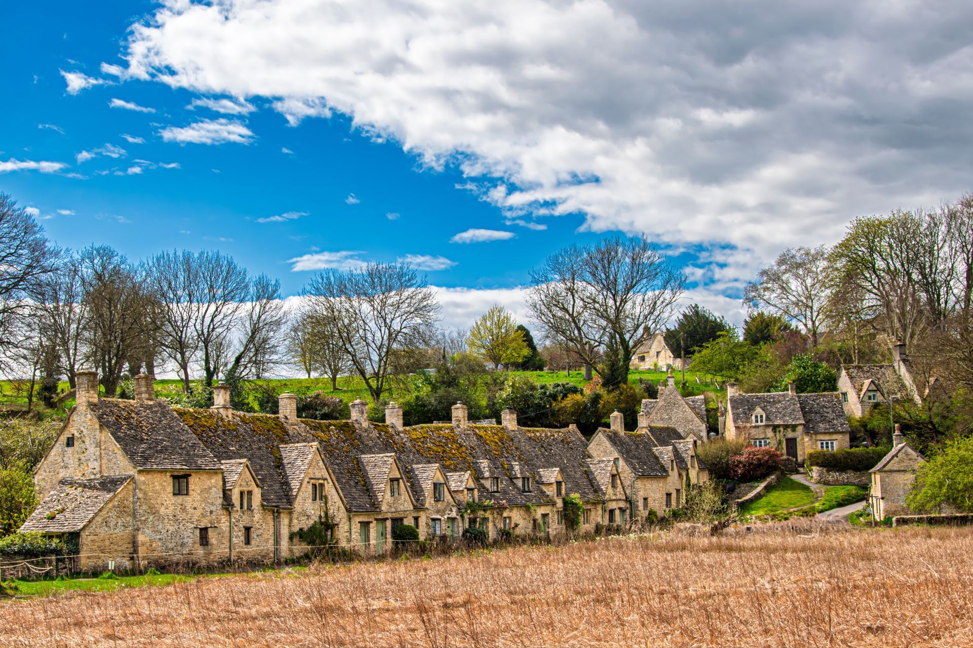 Picturesque Cotswold village with historic stone houses and vibrant spring scenery.