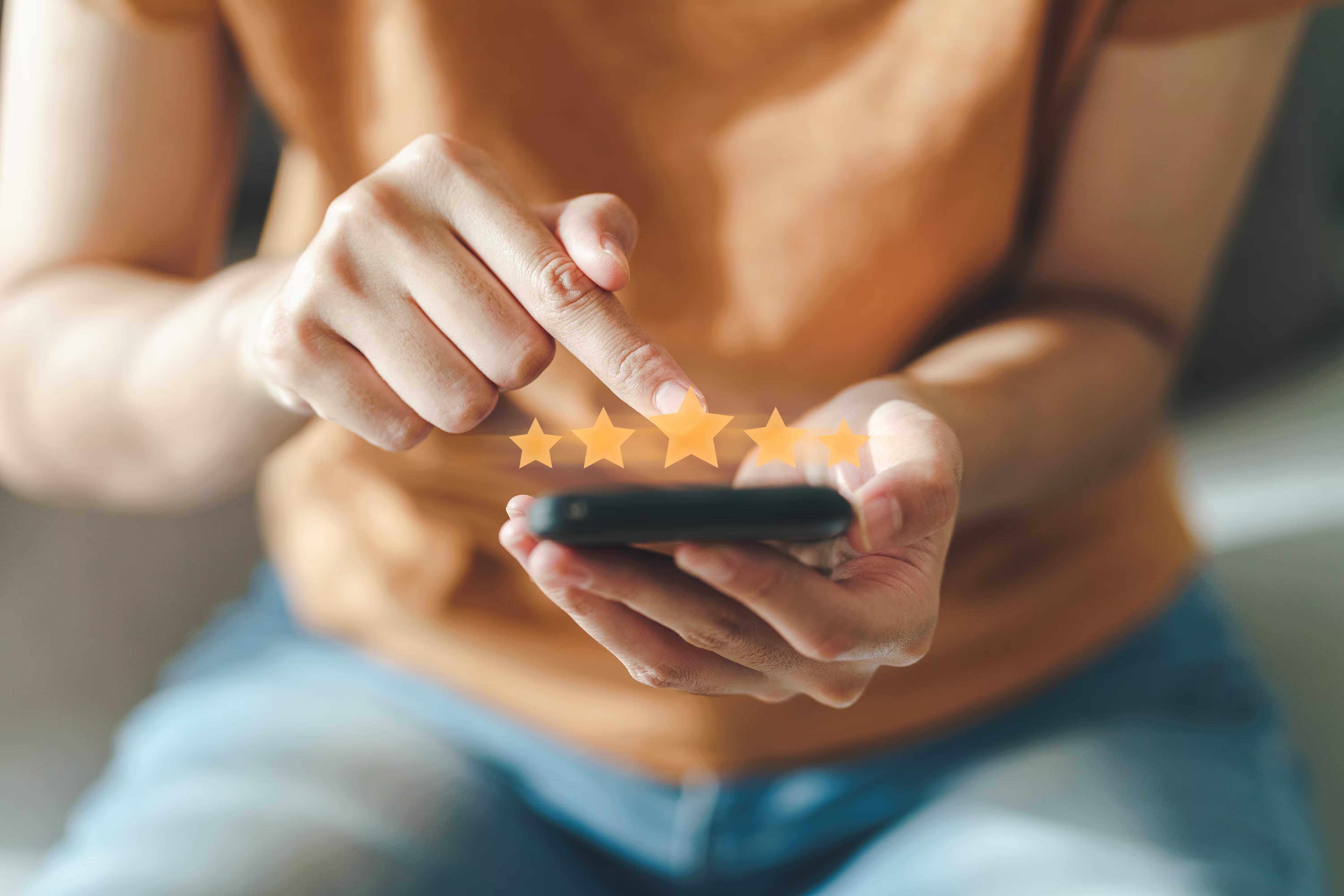 A customer tapping a five-star rating for a local service on a smartphone, the kind of review that decides whether a stranger calls a cleaning company.
