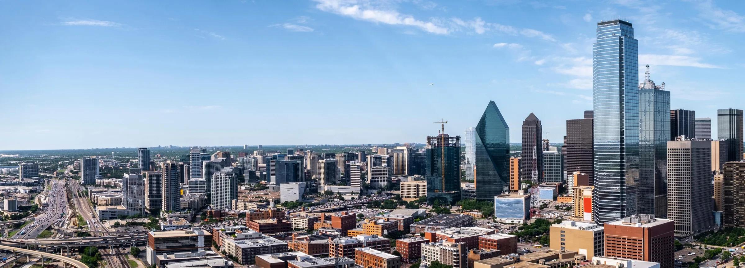 An aerial view of the Dallas skyline under a clear blue sky