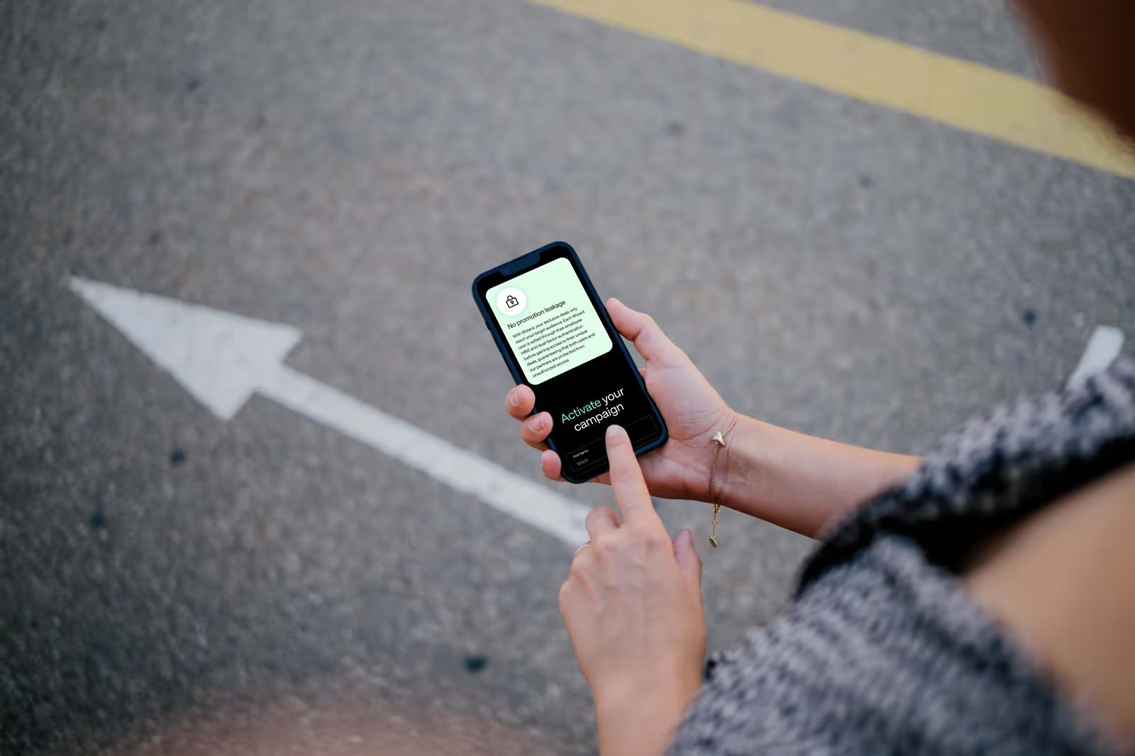 Person holding phone outdoors showing Wizard Perks mobile Activate Your Campaign page