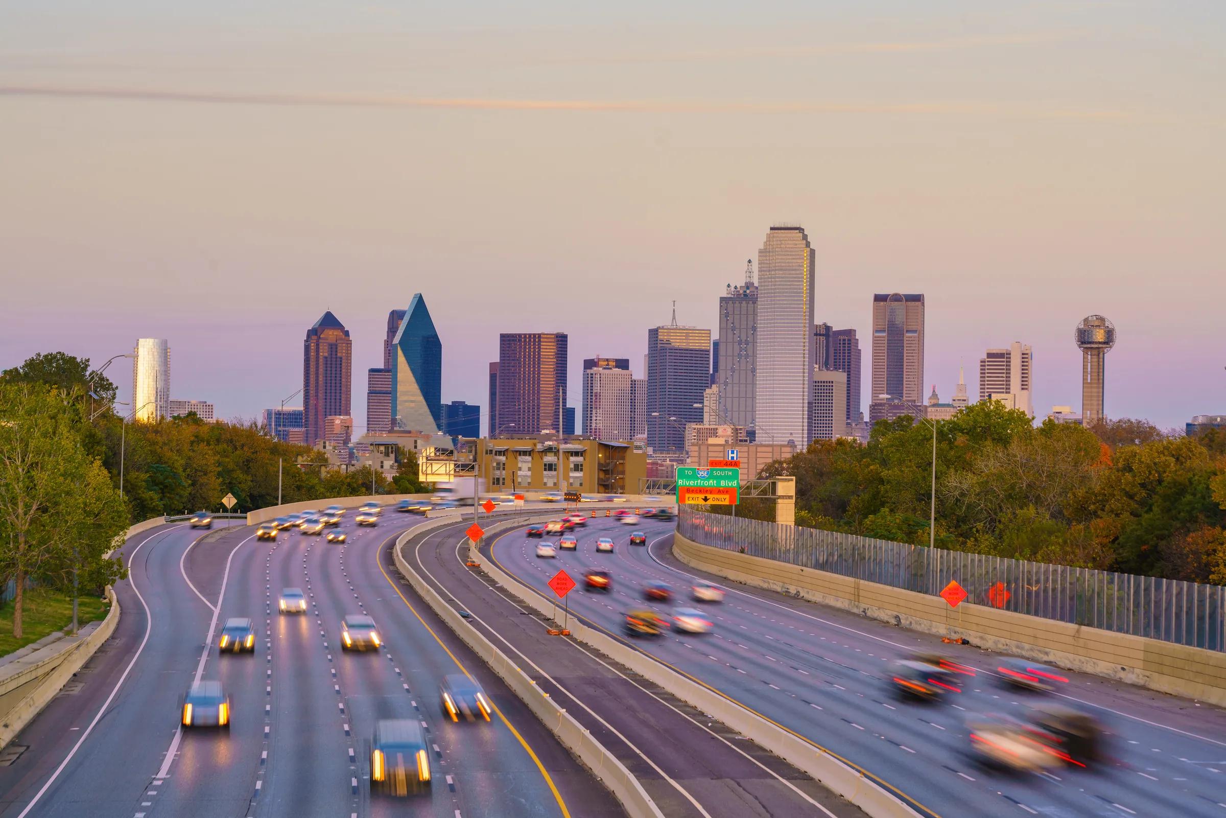 Traffic moving on a North Texas highway with the Dallas skyline behind it
