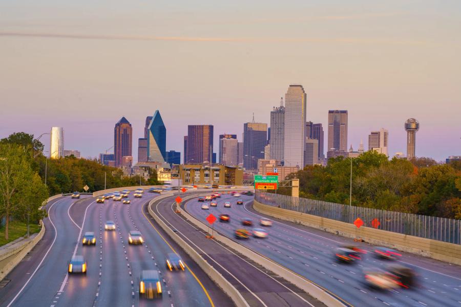 Traffic moving on a North Texas highway with the Dallas skyline behind it