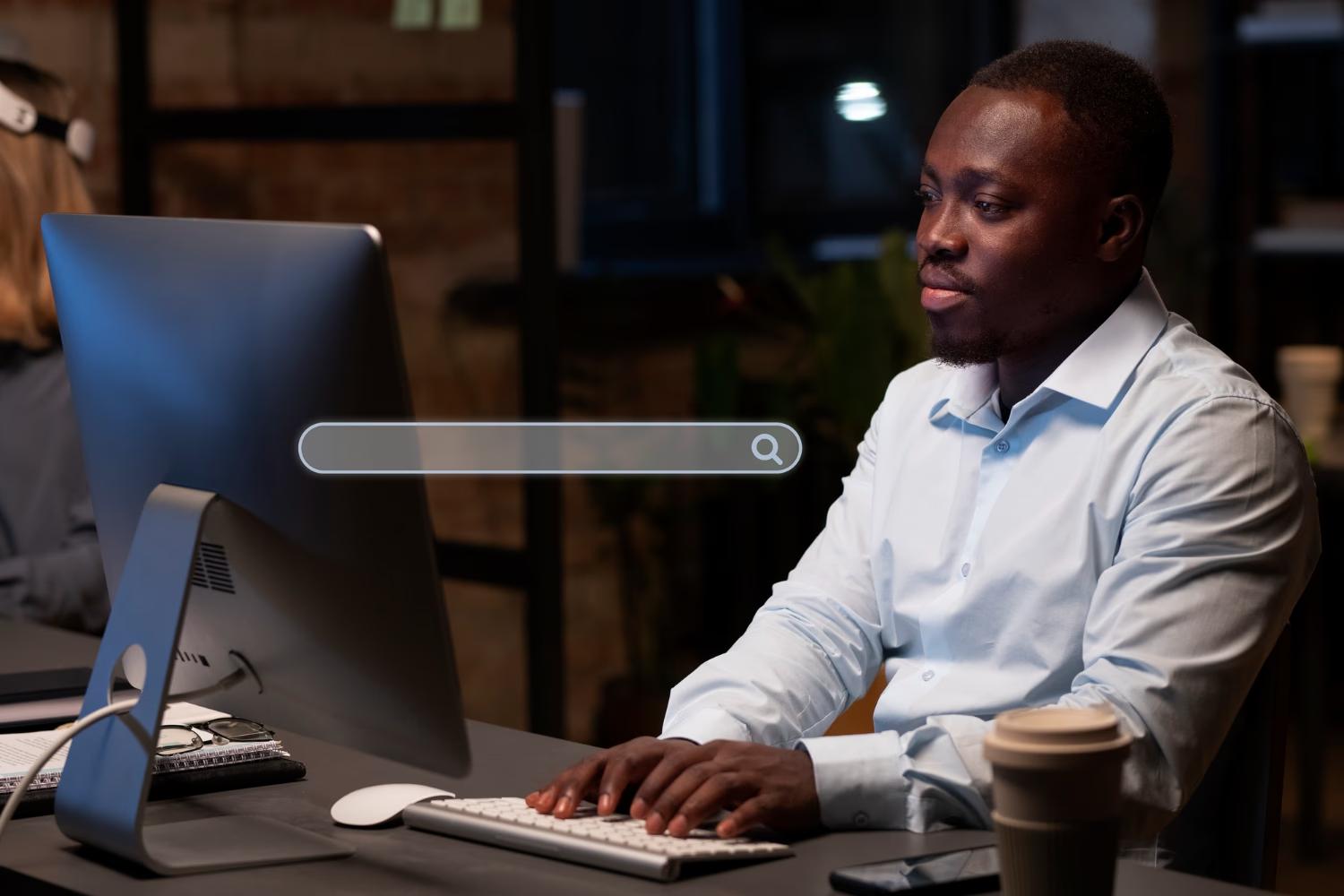 business owner doing research to make adjustments on his search keywords with a search bar showing in foreground while he is sitting at his computer in a darker room