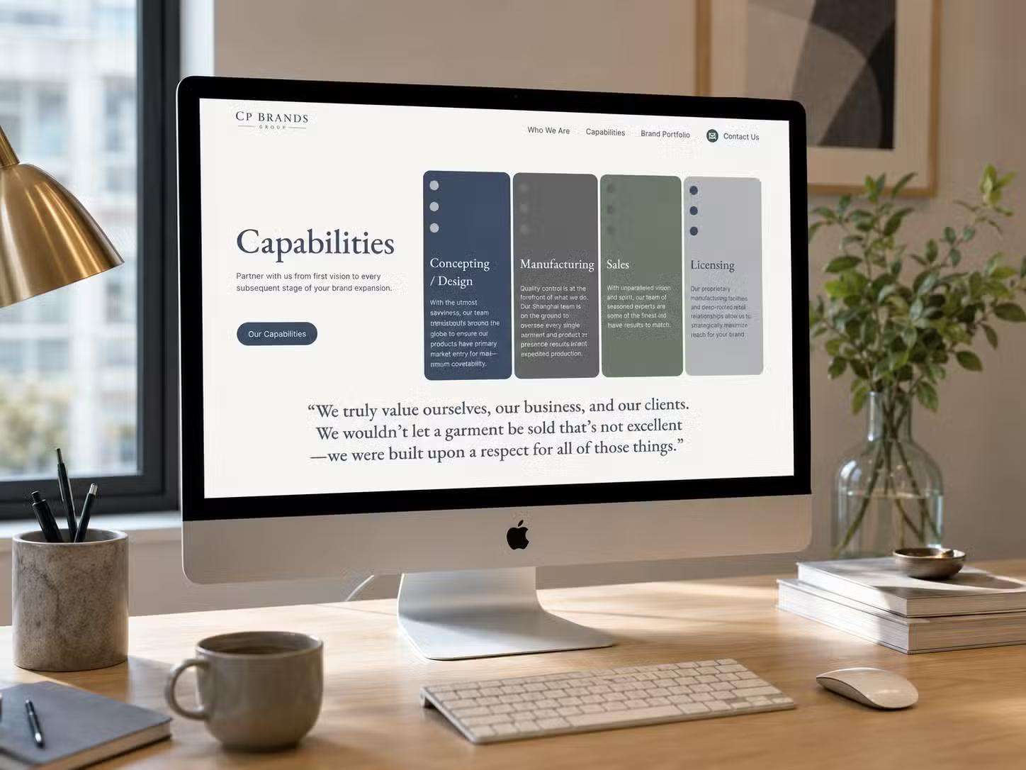 iMac on a home-office desk displaying the CP Brands Group website Capabilities page, with columns for Concepting/Design, Manufacturing, Sales, and Licensing above a client testimonial quote.