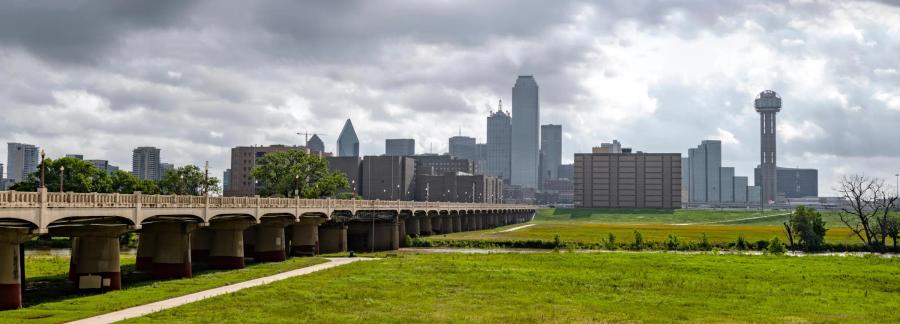 The Dallas skyline seen across the Trinity River levee under heavy cloud