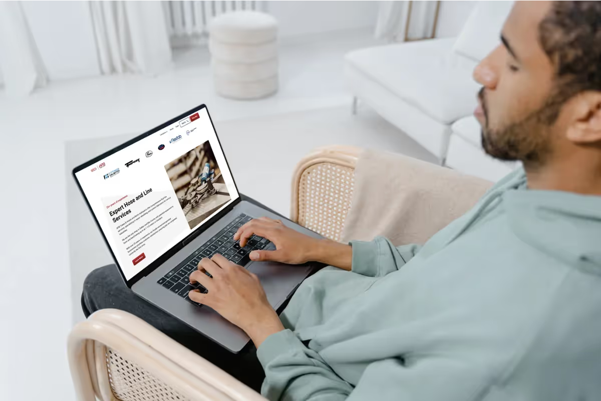Man in a chair using a laptop showing the Fluid Line Solutions supplier logos and Expert Hose and Line Services section