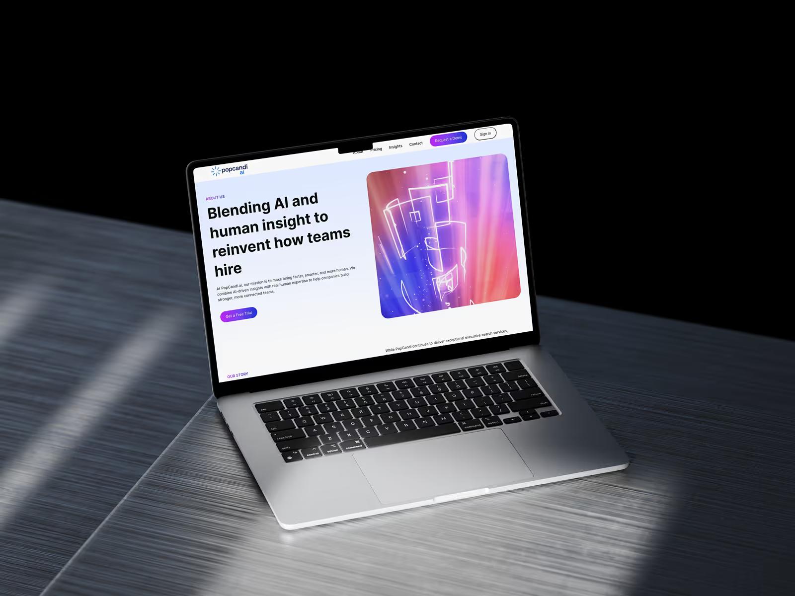 MacBook on dark metallic surface displaying PopCandi AI About page hero with Blending AI and human insight headline and colorful abstract graphic