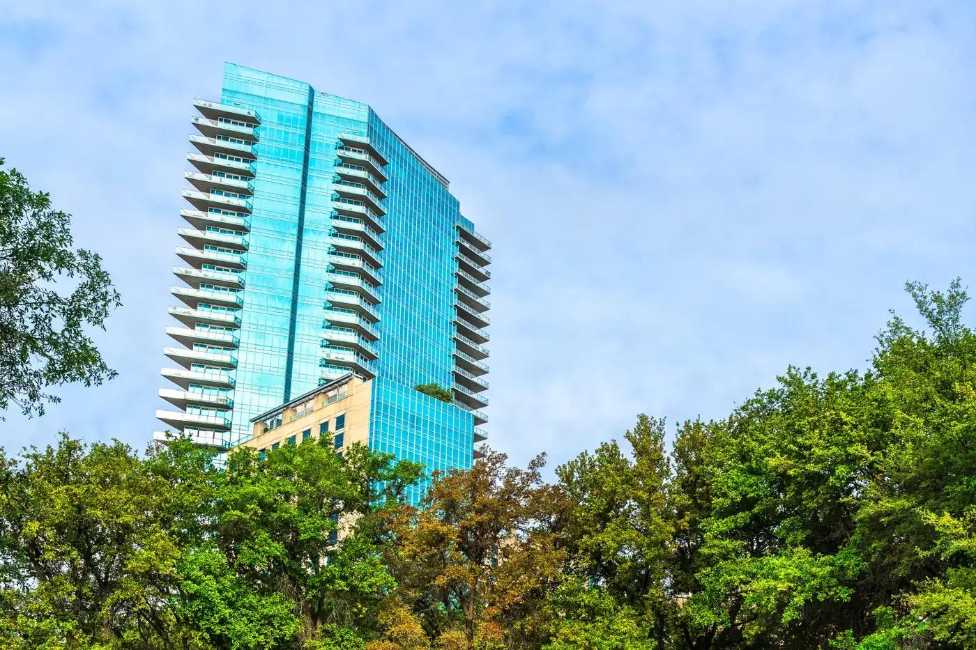 A glass office tower rising above the treeline in North Texas