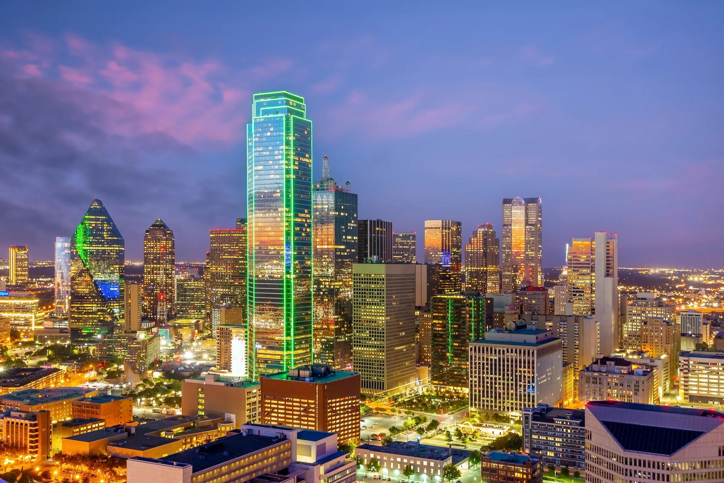 An aerial view of Downtown Dallas at dusk under a purple sky