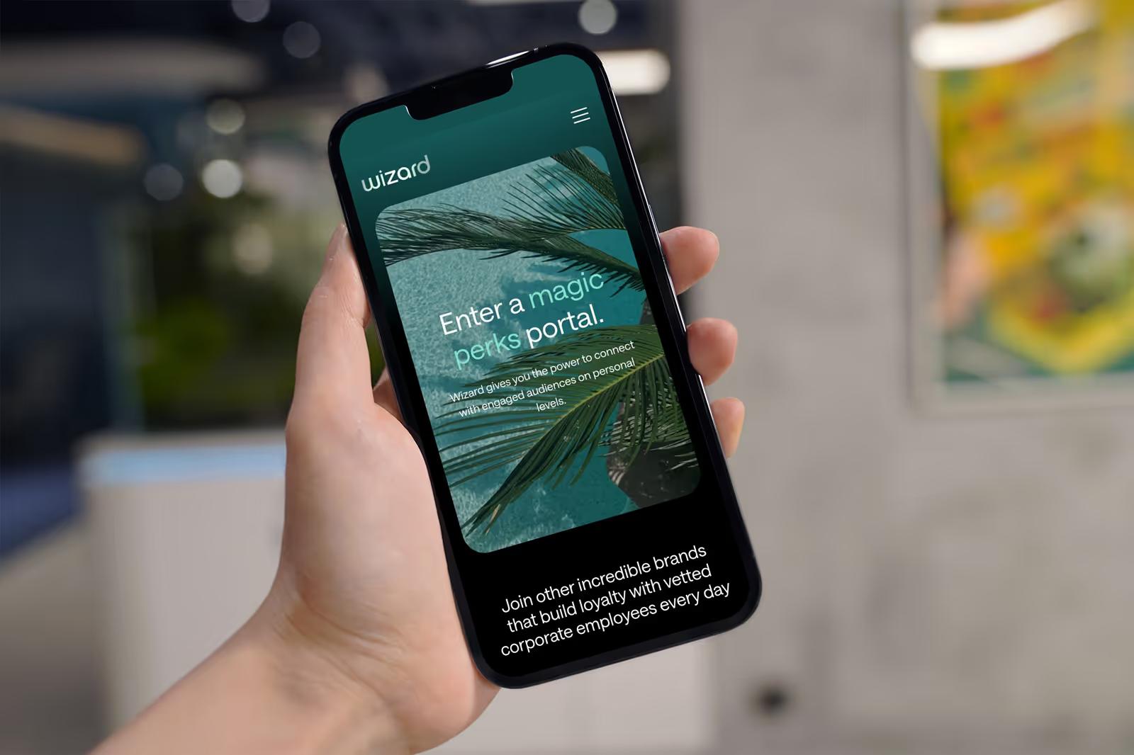 Hand holding phone displaying Wizard Perks mobile hero with Enter a Magic Perks Portal headline