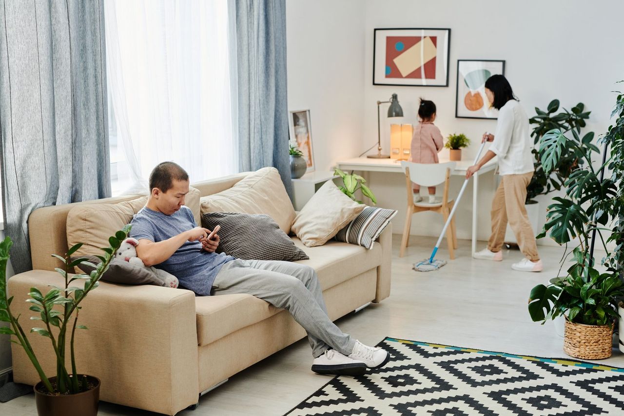Parent helping a child review screen-time settings on a smartphone beside a laptop