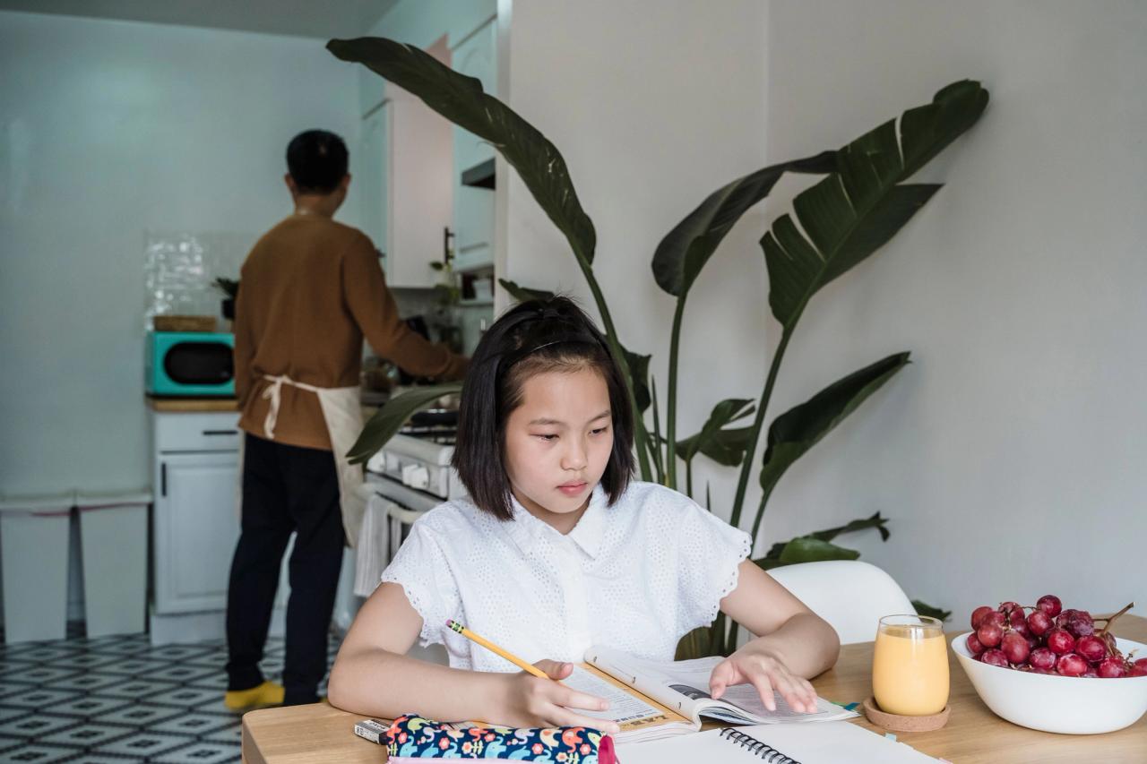 Une fillette fait ses devoirs à la table de la salle à manger