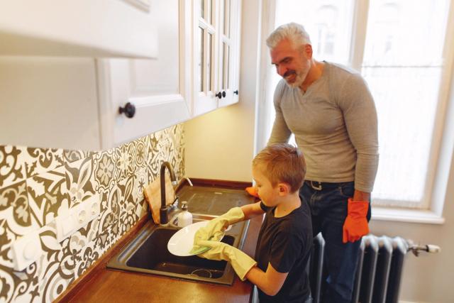 Un père et son fils font la vaisselle ensemble dans la cuisine