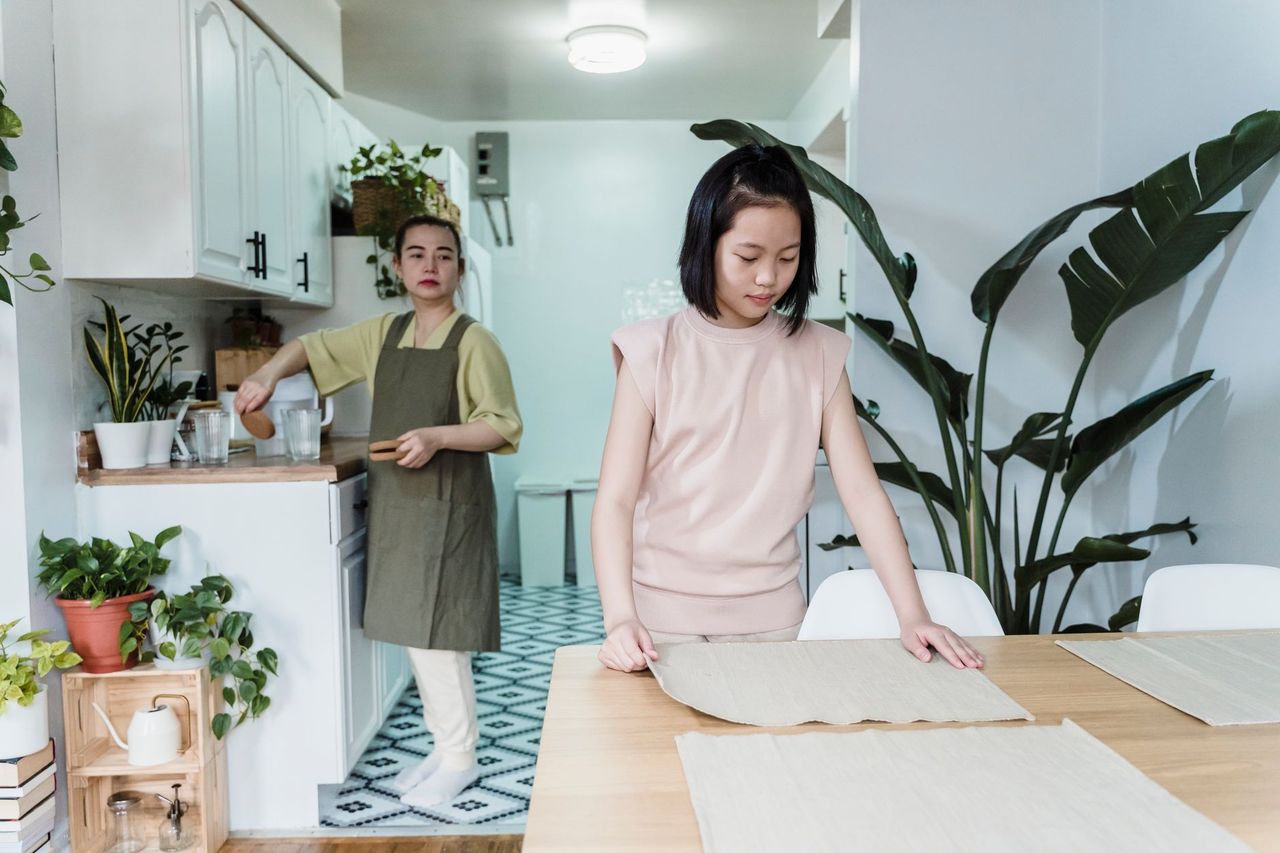 Parent and child reviewing a simple family responsibility board in the kitchen