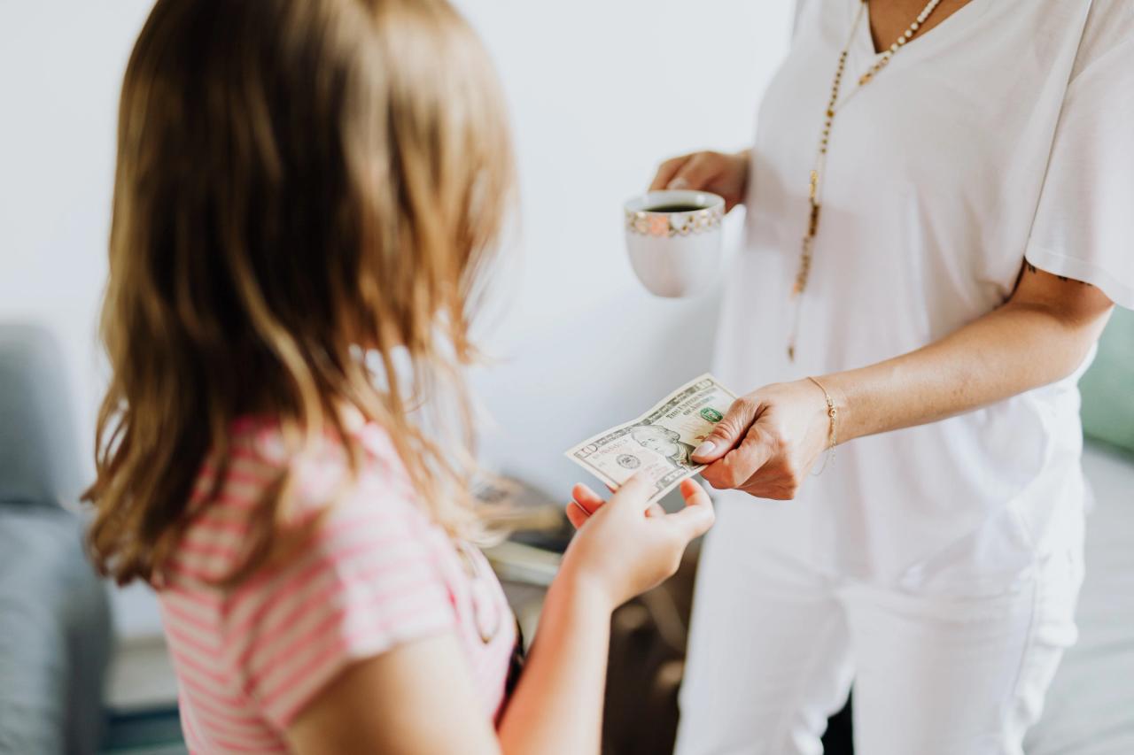 Une mère tend un billet à sa fille en tenant une tasse de café 