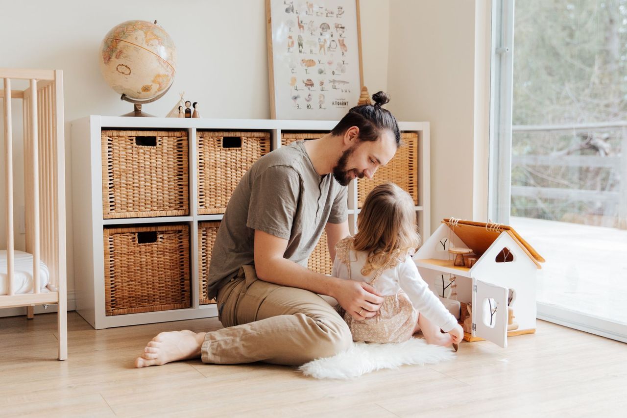 Parent donnant à un enfant une consigne simple près d’un panier de linge