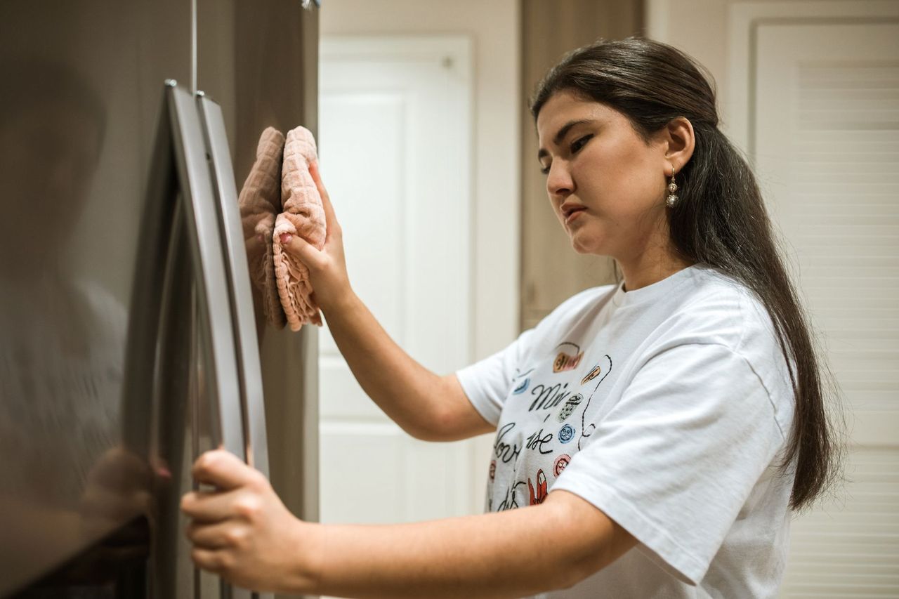 Siblings looking together at a family chore chart on a kitchen wall