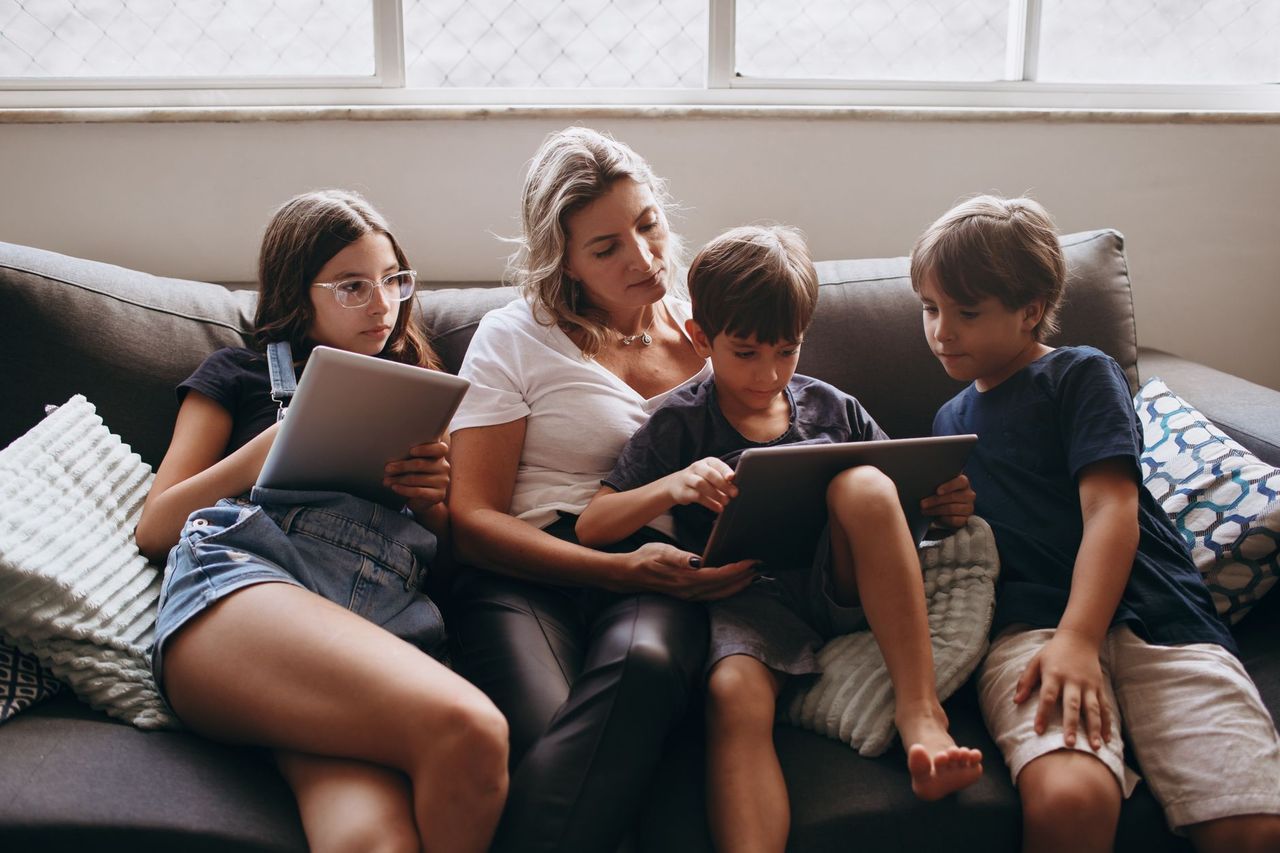 Parent and child reviewing a shared family calendar on a tablet at the kitchen table