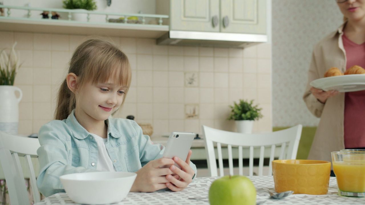 Parent and child reviewing a signed screen time contract beside a charging station