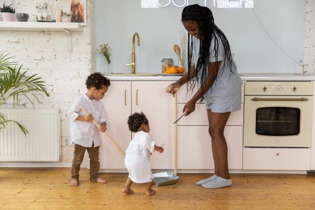 Une mère et ses deux enfants rangent ensemble dans une cuisine lumineuse