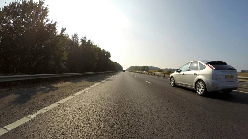 серебряный Ford Focus 5 дверный хэтчбек, мчащийся по дороге