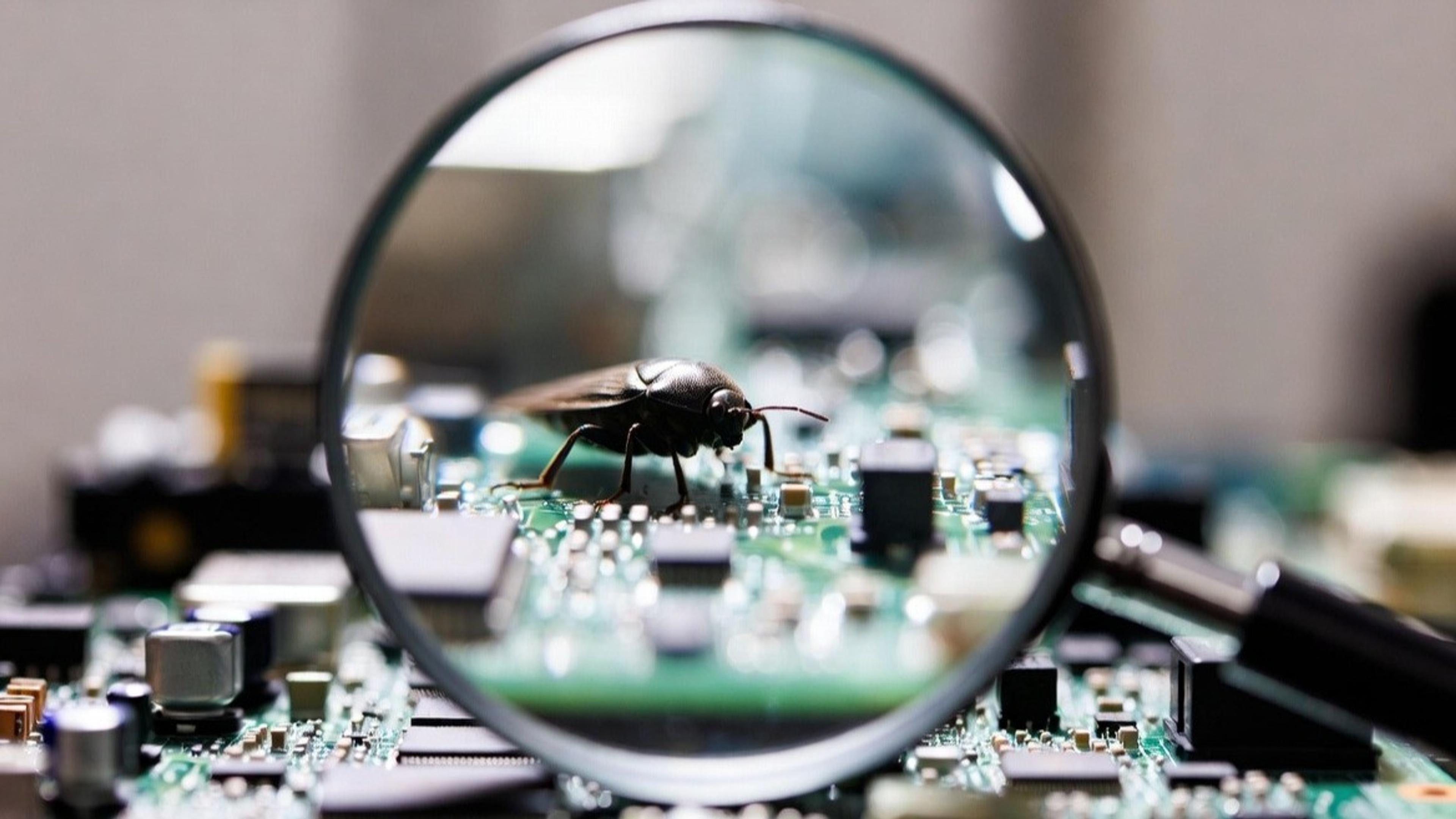 A magnifying glass magnifies a bug crawling on a circuit board.