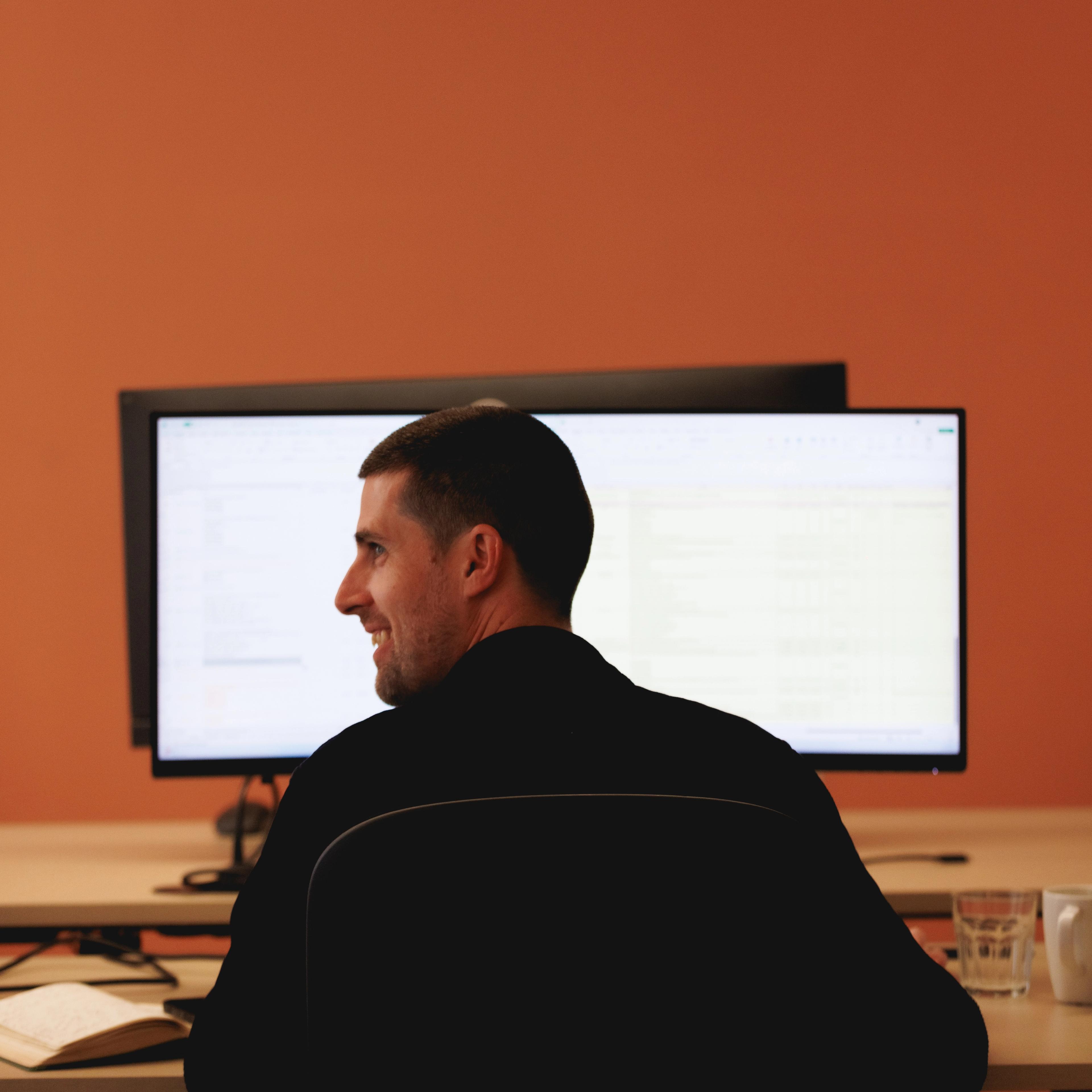 a man is sitting at a desk in front of a computer monitor .