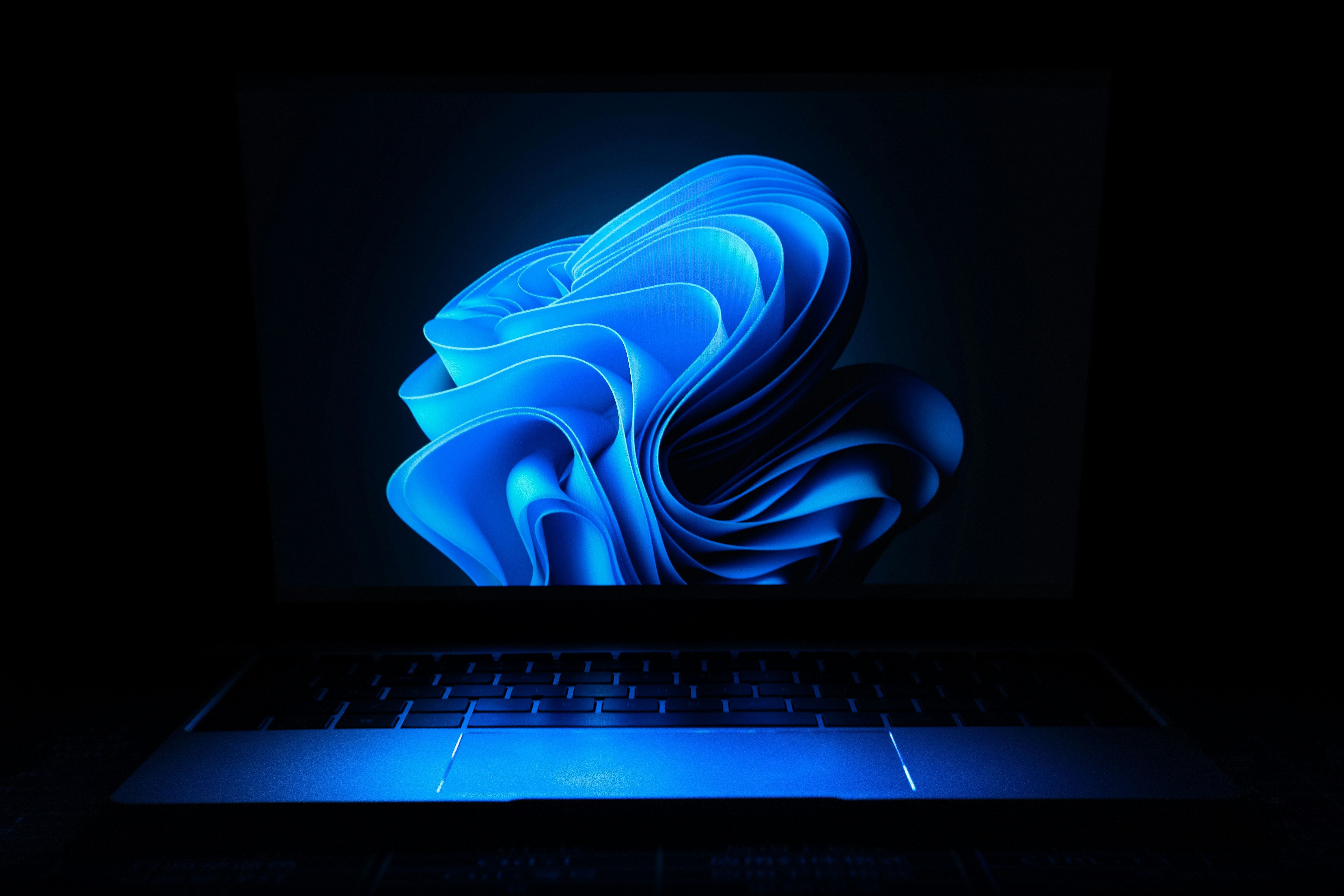the windows 11 logo is displayed on the screen of a laptop computer .