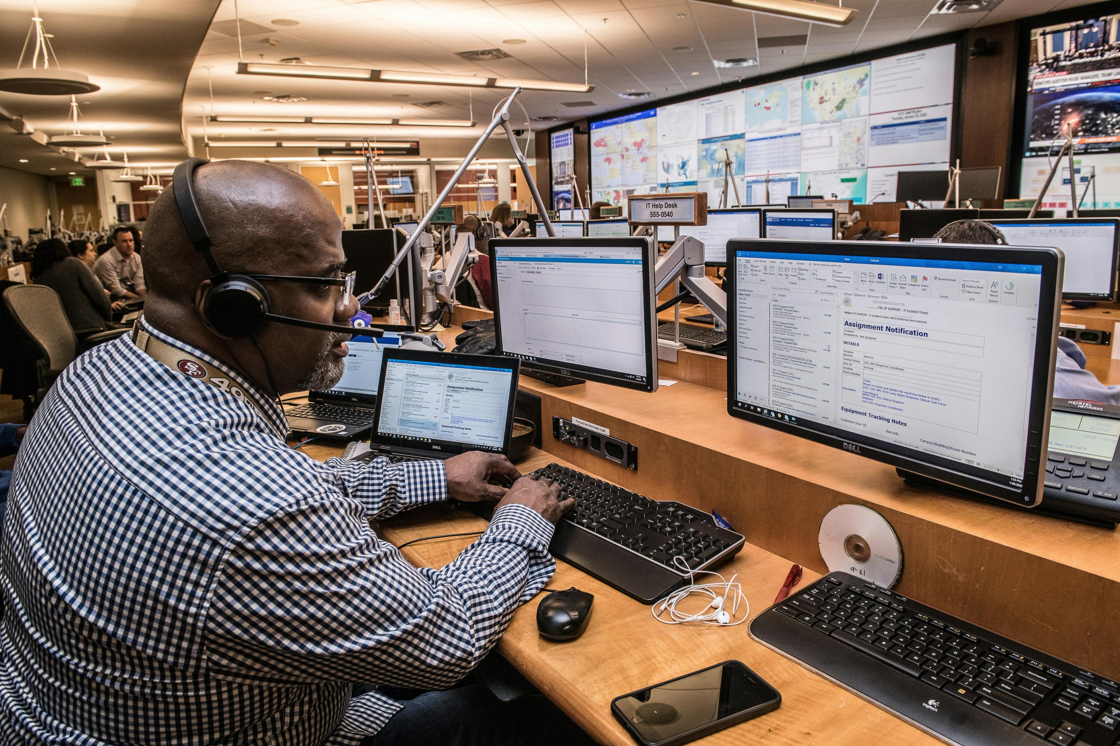 a man wearing a headset is sitting at a desk in front of a computer .