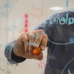 a person is writing on a whiteboard with a marker .