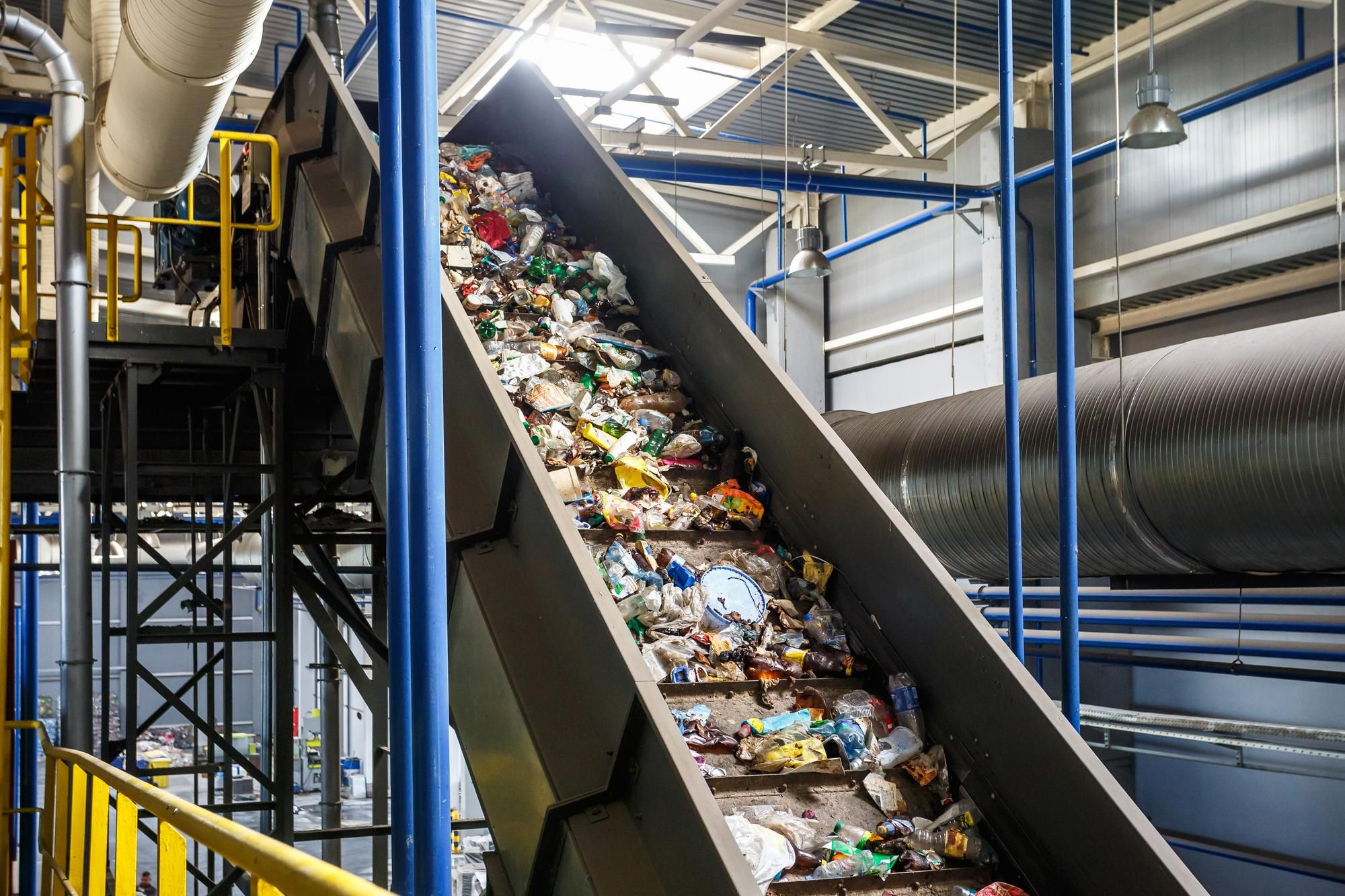 a conveyor belt filled with garbage in a factory .