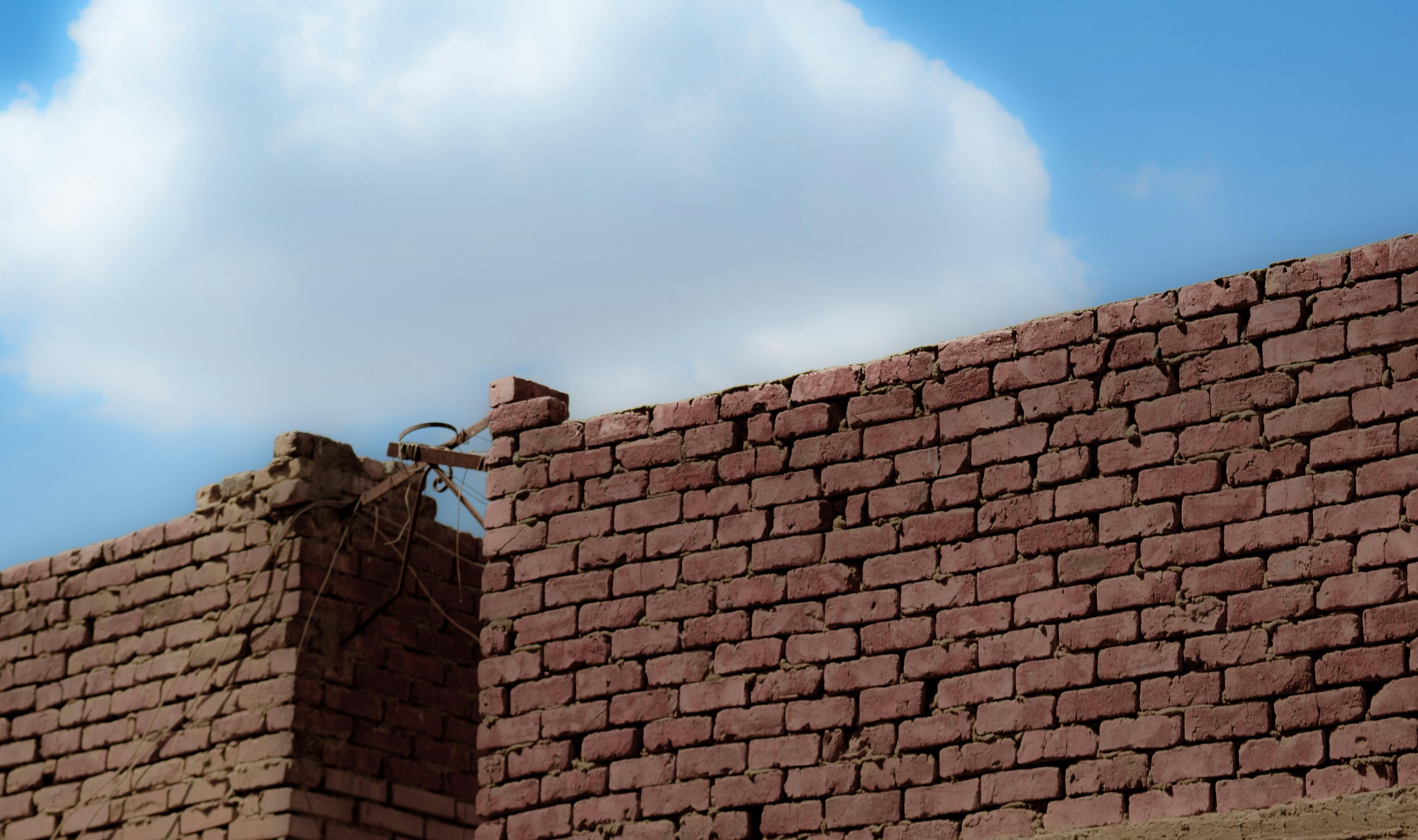 a brick wall with a cloud in the sky behind it .