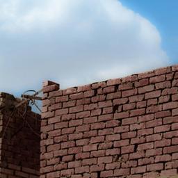 a brick wall with a cloud in the sky behind it .