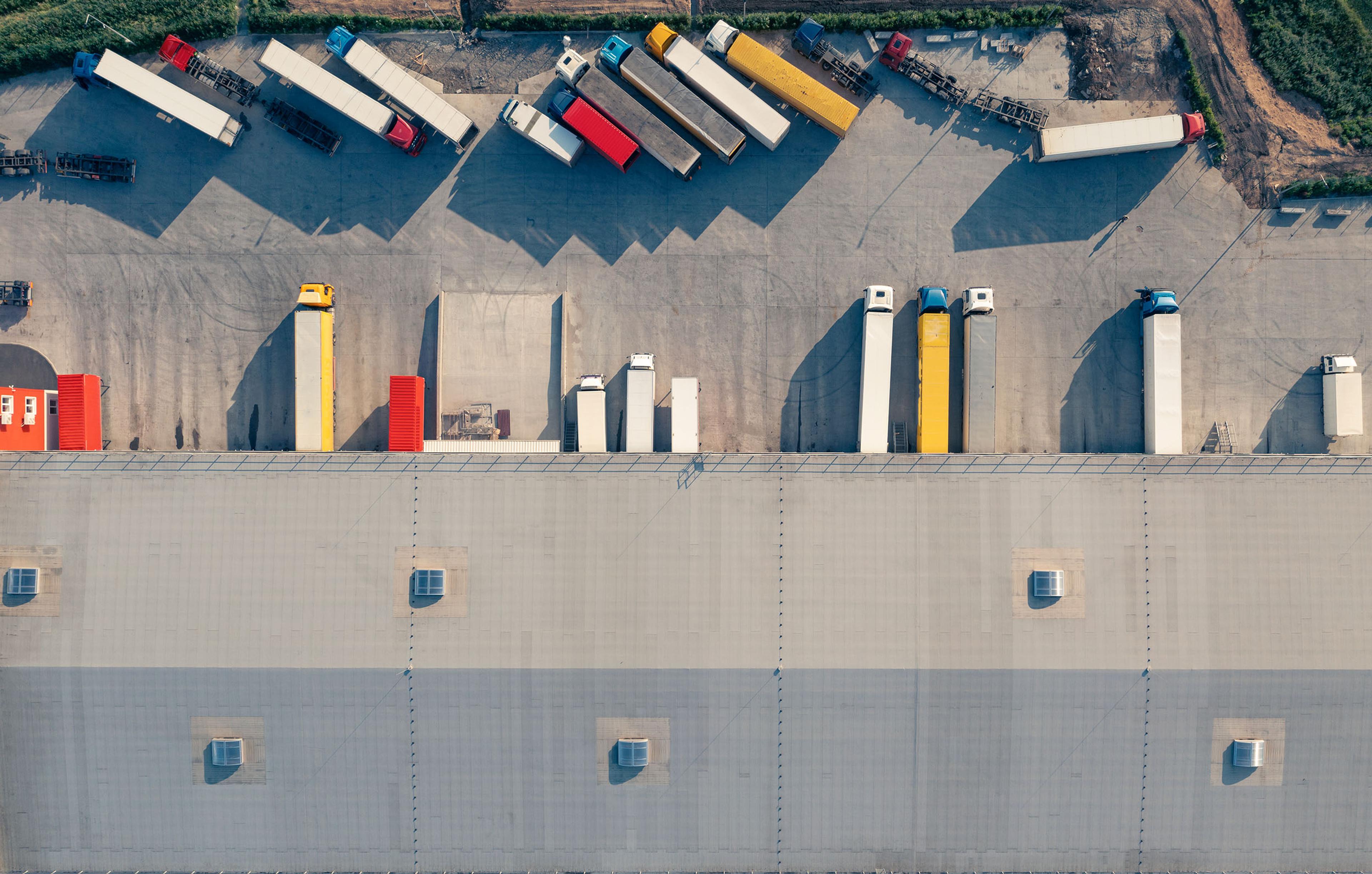 an aerial view of a warehouse with trucks parked in front of it .