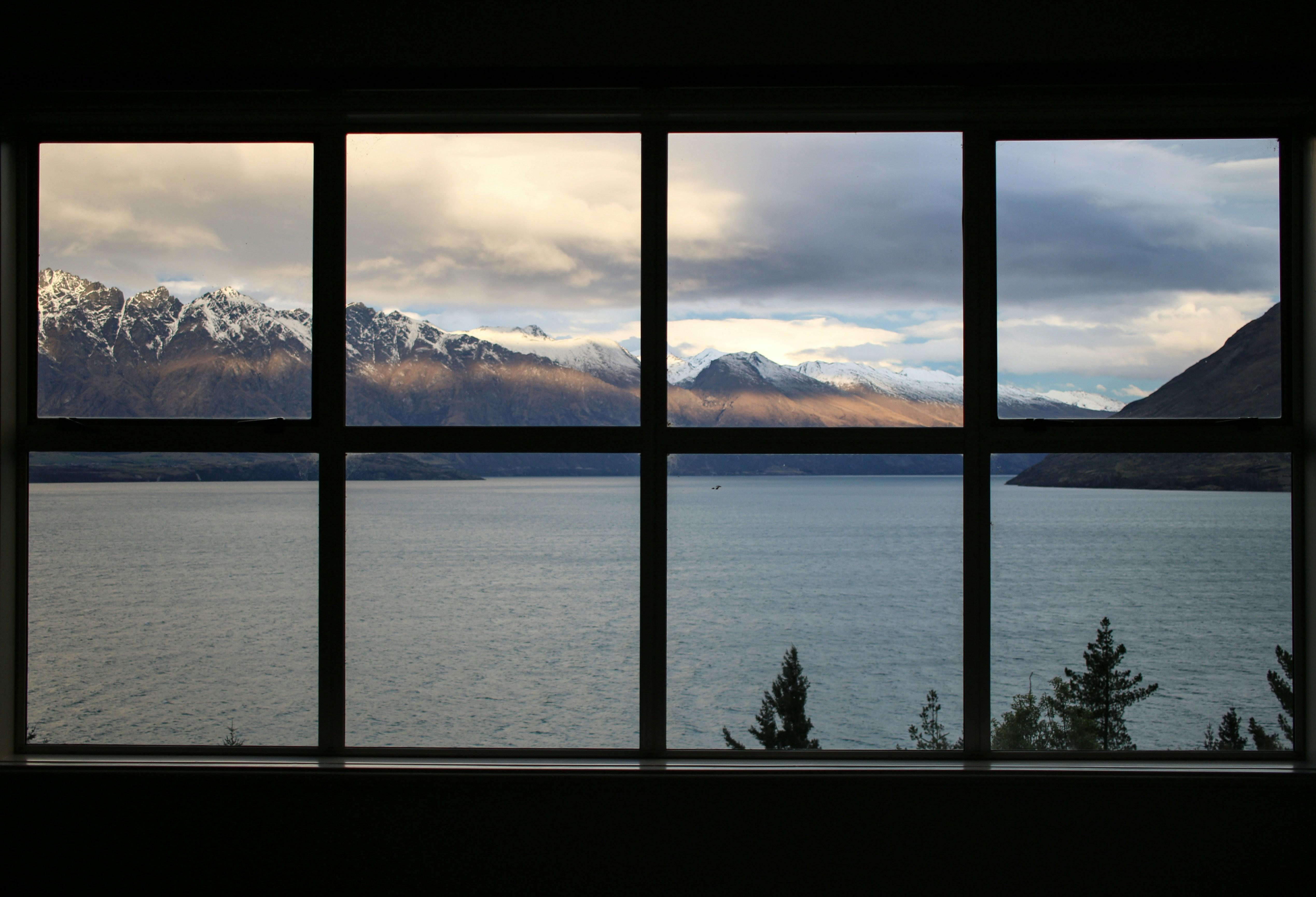 a window with a view of a lake and mountains